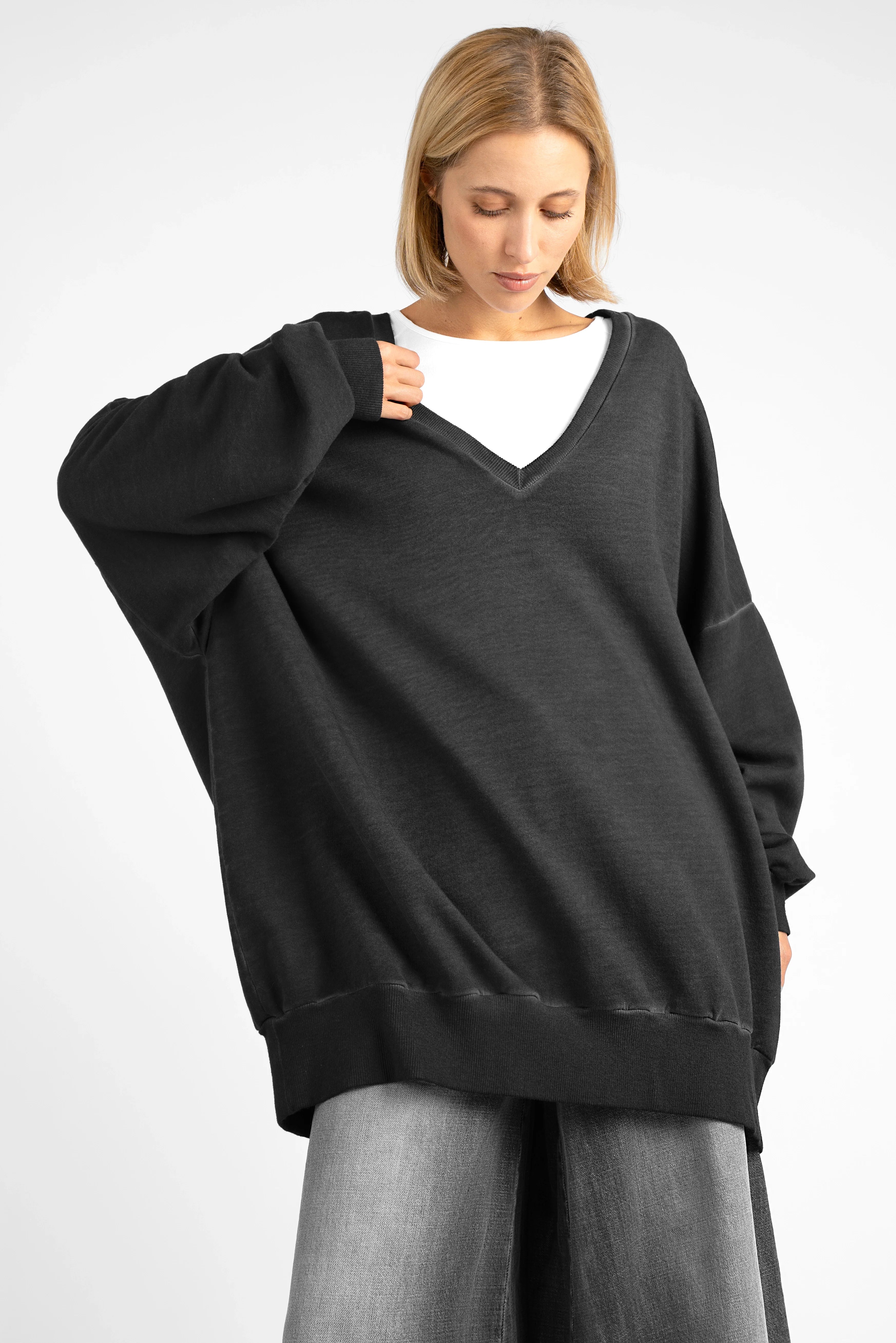 Woman wearing oversized black IMIKO Studio Long-Sweater with deep V-neck and dropped shoulders