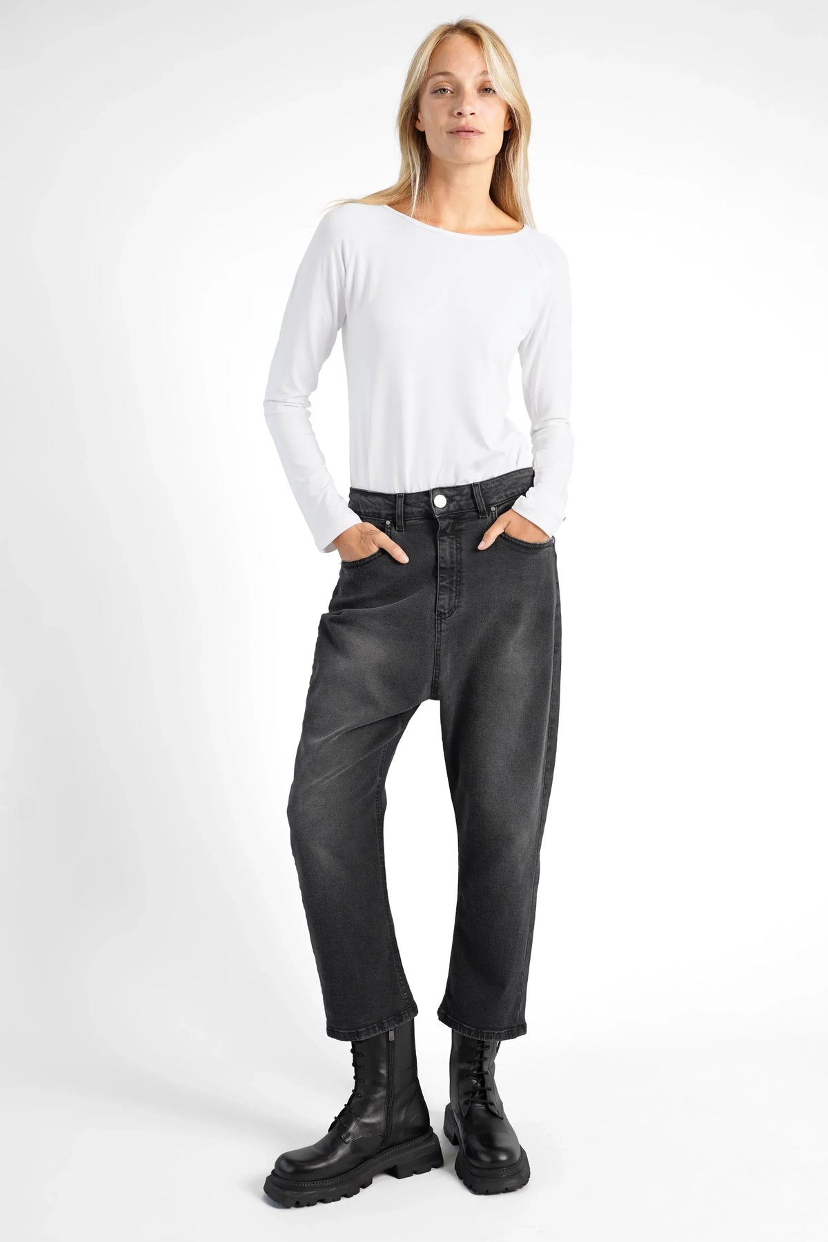 Damen trägt schwarze JEANY Baggy Jeans mit destroyed Waschung und relaxed Fit kombiniert mit weißem Langarmshirt und schwarzen Stiefeln