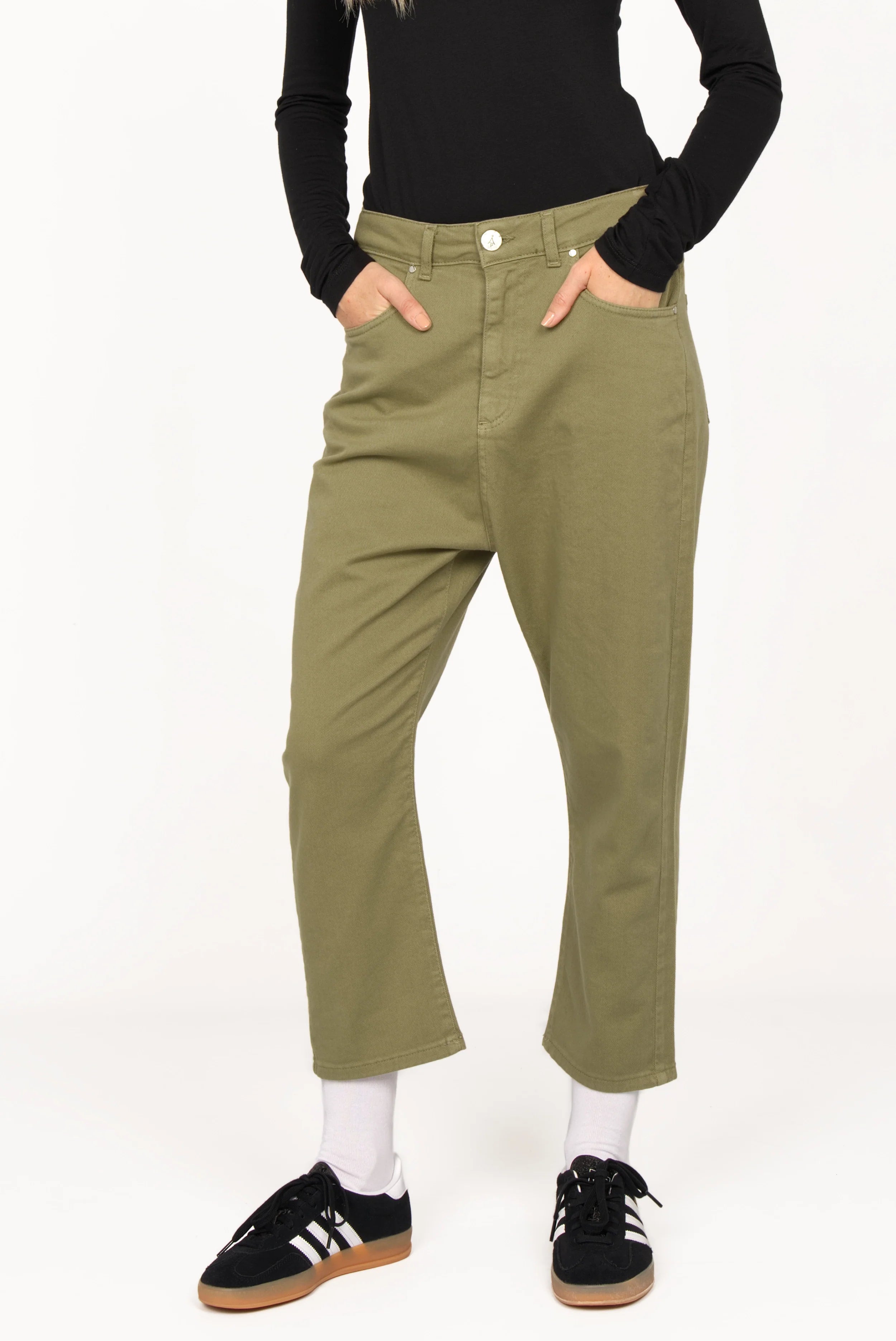Relaxed fit olive green baggy jeans with 5-pocket design and zip fly on model wearing black top and sneakers