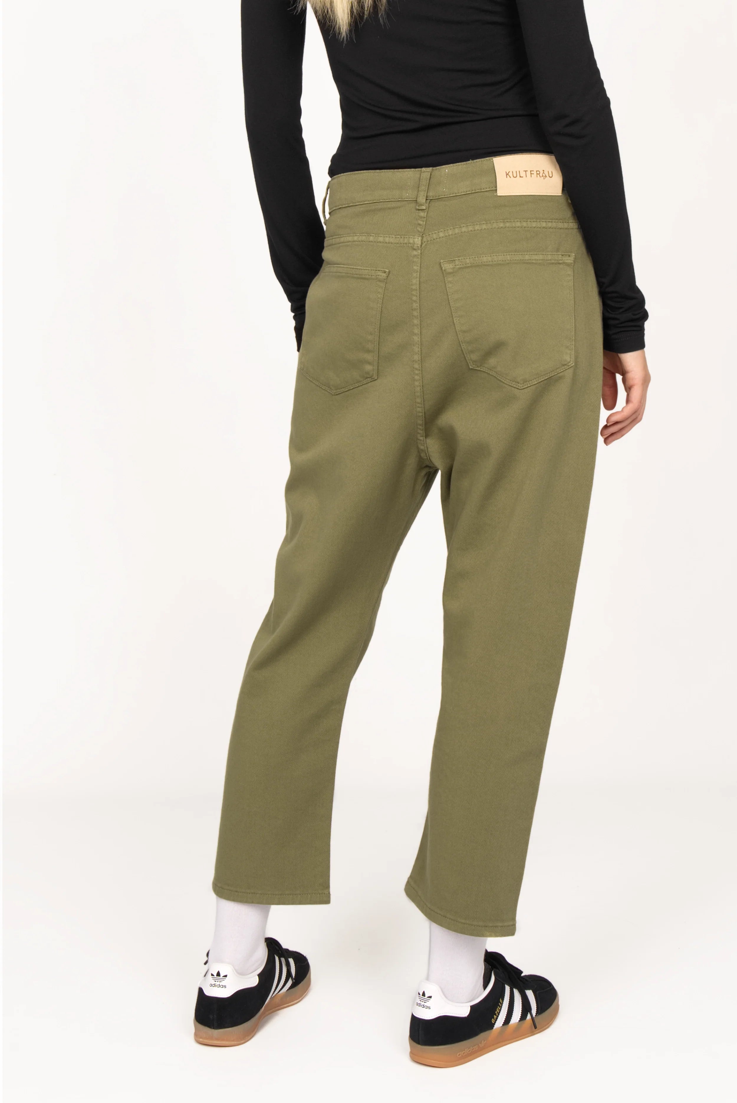 Olive green relaxed fit baggy jeans with a loose waistband and deep crotch, styled with a black top and sneakers.