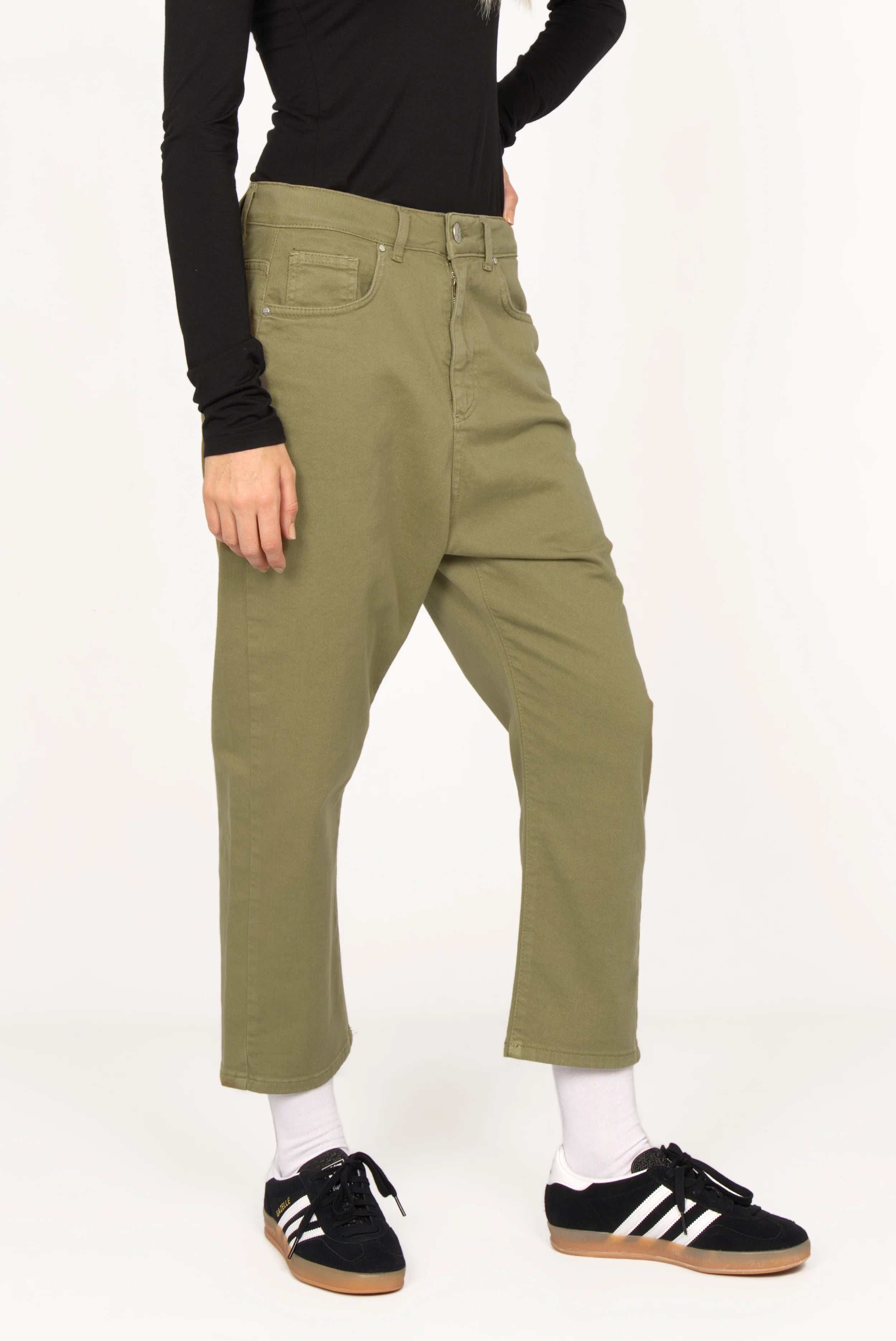 Relaxed fit olive green baggy jeans with deep crotch and 5-pocket design worn with black top and sneakers
