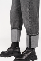 Grey baggy jeans with wide cuff and faded wash paired with black leather boots