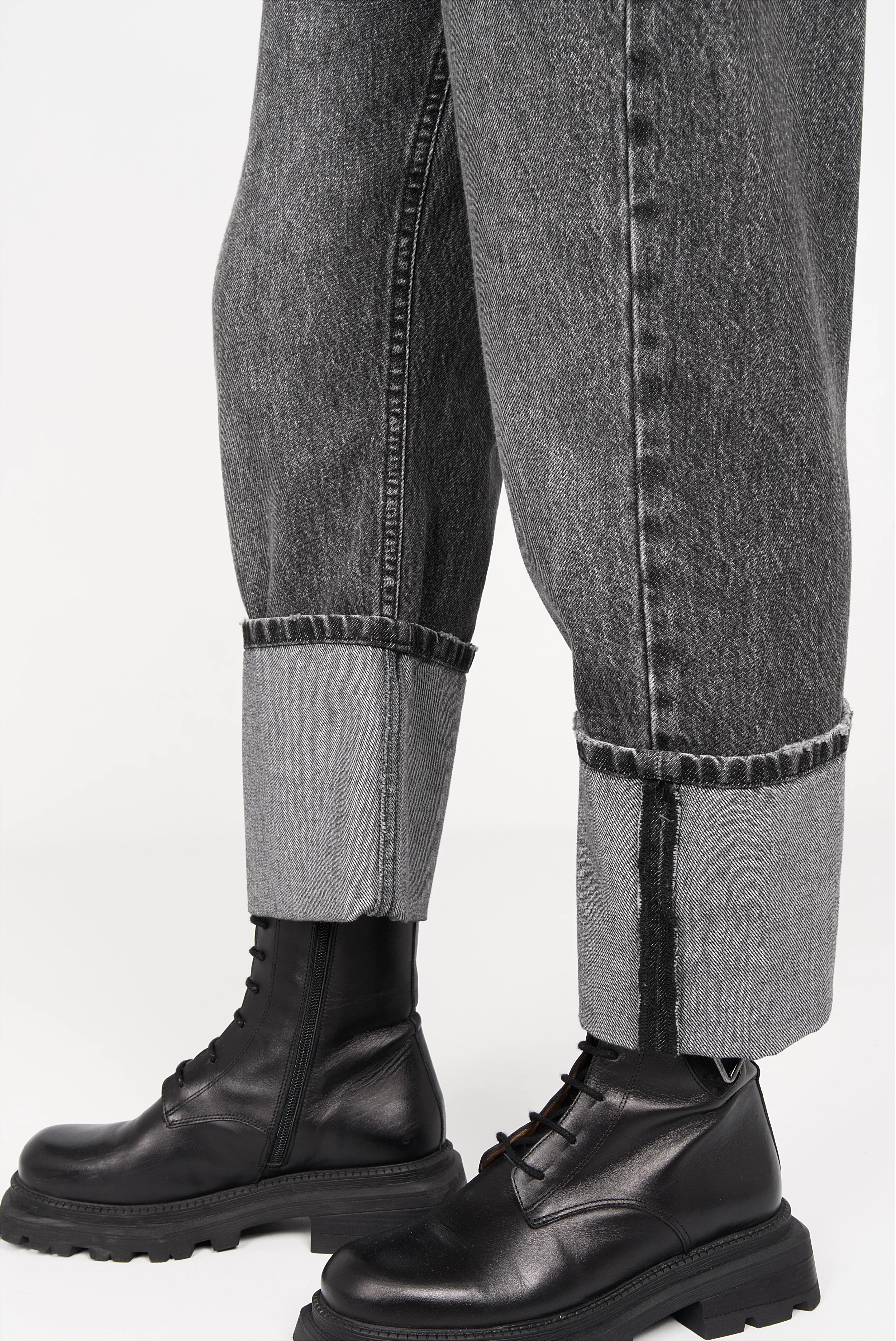 Grey baggy jeans with wide cuff and faded wash paired with black leather boots