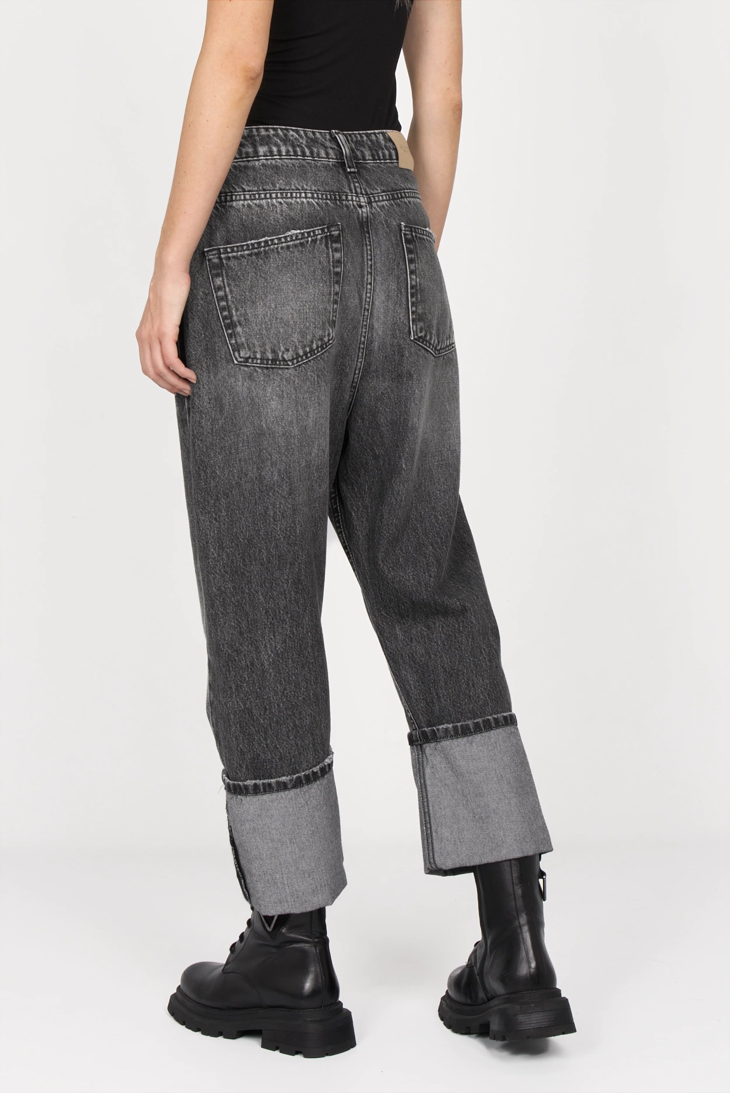 Back view of black washed baggy jeans with wide fixed cuffs and relaxed fit, styled with black boots.