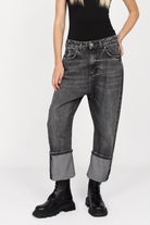 Black washed baggy jeans with wide fixed cuffs and relaxed fit on model wearing black boots