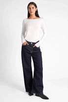 Damen in handgefertigten JOOSY Wide Leg Jeans mit weitem Bein und relaxed Fit, kombiniert mit weißem Langarmshirt.