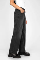 Woman wearing black JOOSY Wide Leg Jeans with relaxed fit and normal waist, styled with black boots and white top.