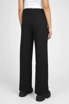 Back view of black KANDANEA Gerade Hose straight-leg pants with elastic waistband and small hem slits worn by model
