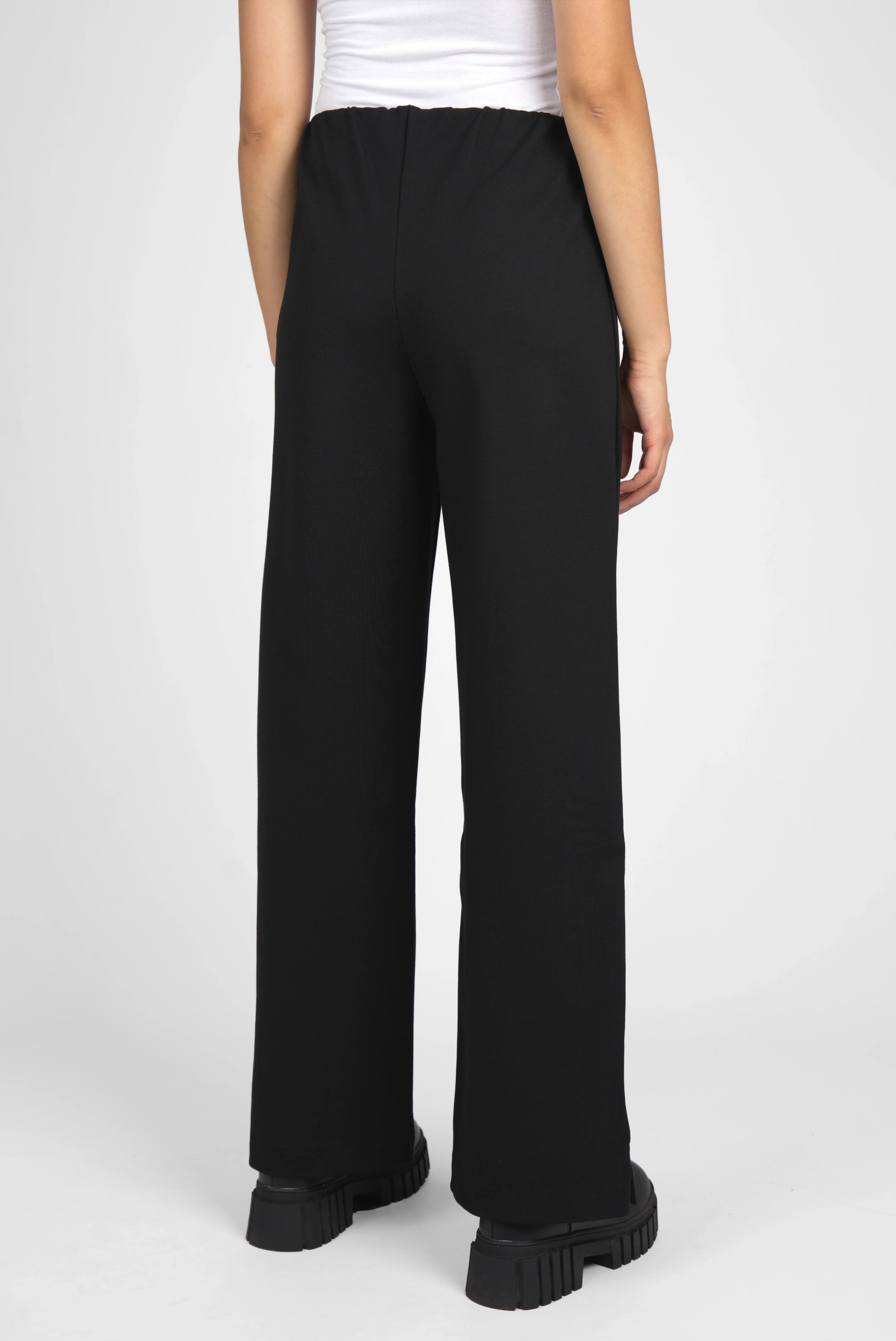 Back view of black KANDANEA Gerade Hose straight-leg pants with elastic waistband and small hem slits worn by model