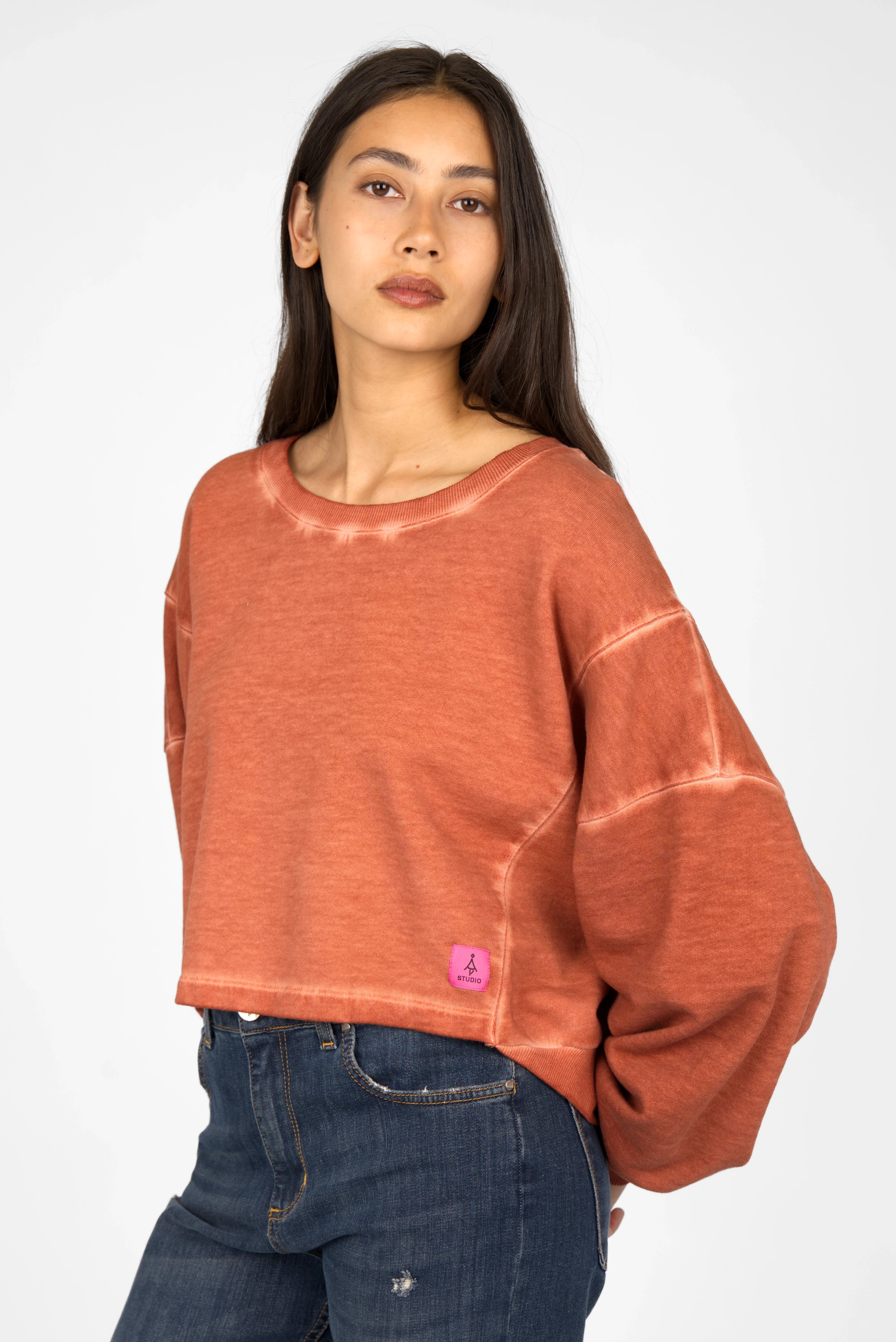 Woman wearing oversized KERY Cropped Sweater with U-boat neckline in cold-washed cotton and pink studio logo patch.