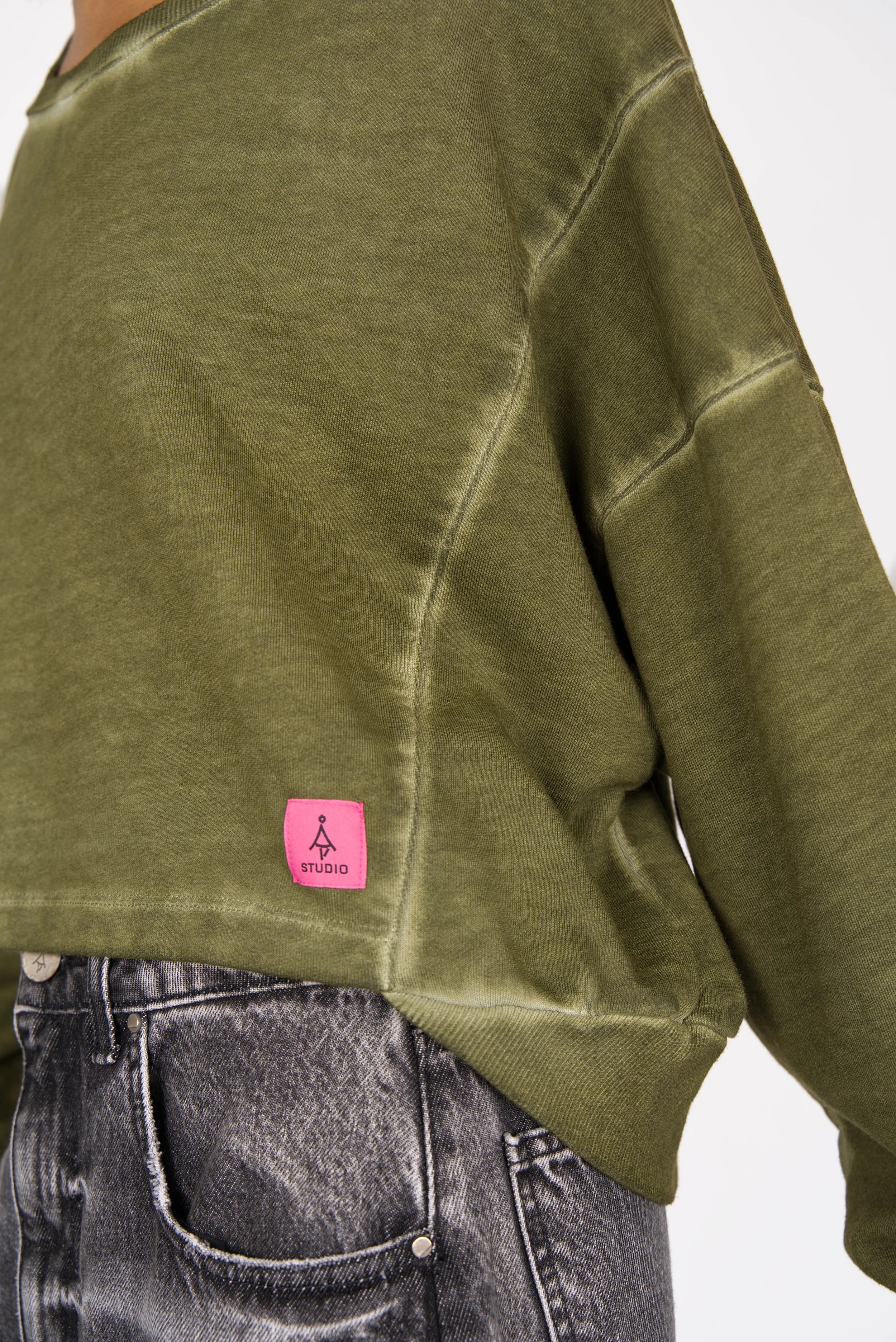 Green KERY Cropped Sweater with oversized fit, boat neckline, dropped shoulders, pink STUDIO logo patch, and cold-washed cotton fabric.