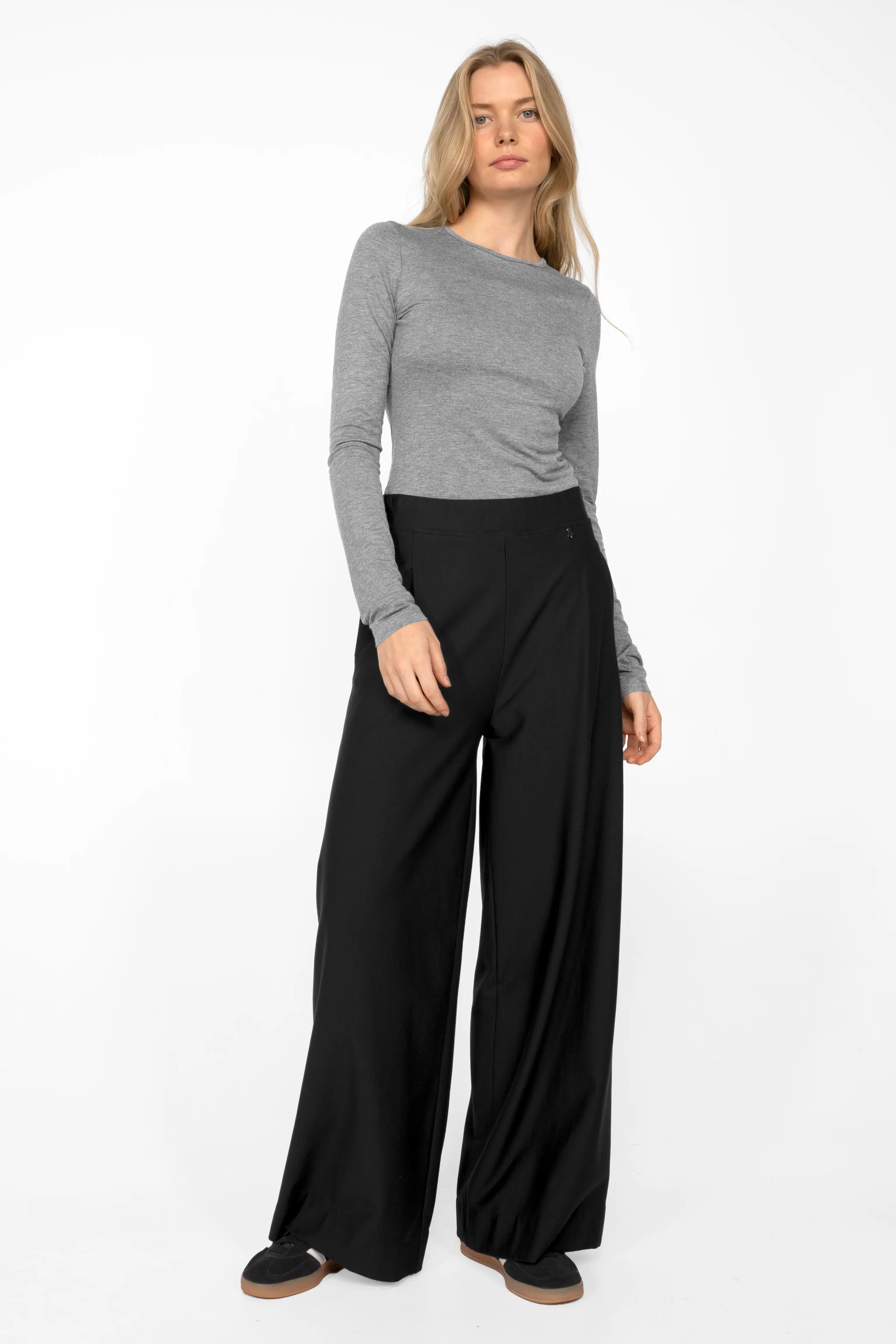 Damen trägt schwarze KLARA.K Wide Leg Pants mit weitem Schnitt und elastischem Bund kombiniert mit grauem Langarmshirt