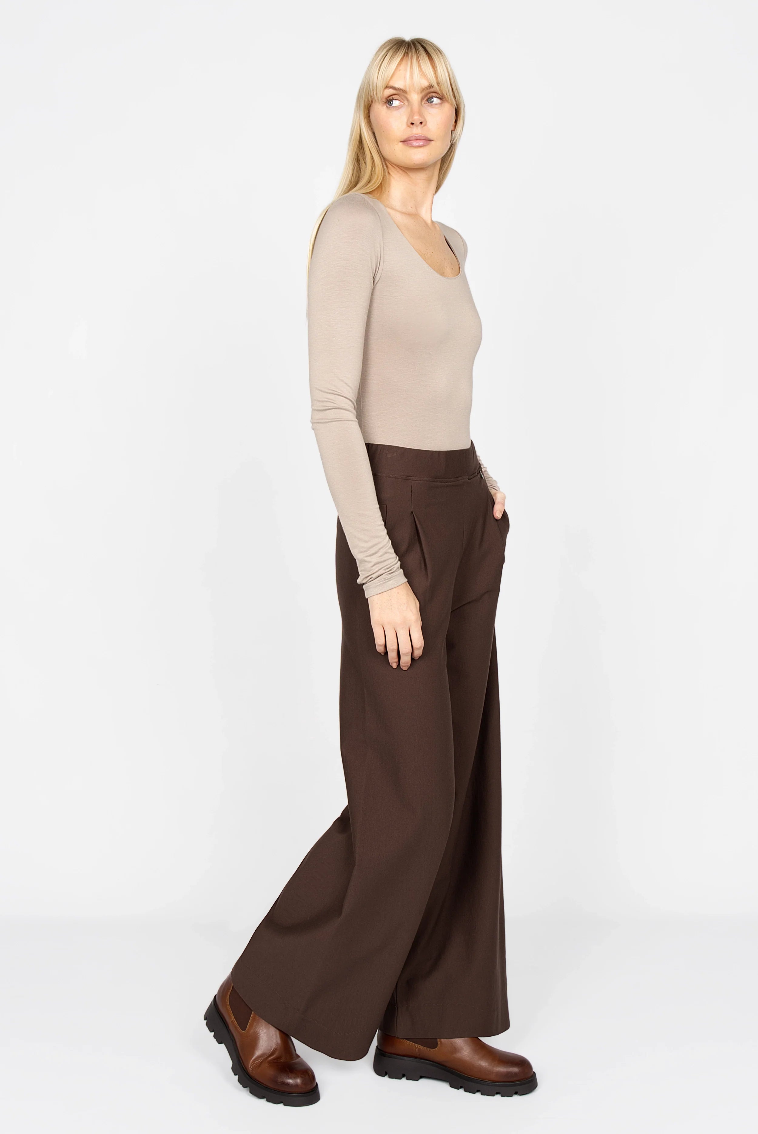 Frau trägt KLARA.K Wide Leg Pants mit weitem Schnitt, elastischem Bund und seitlichen Taschen in Braun.