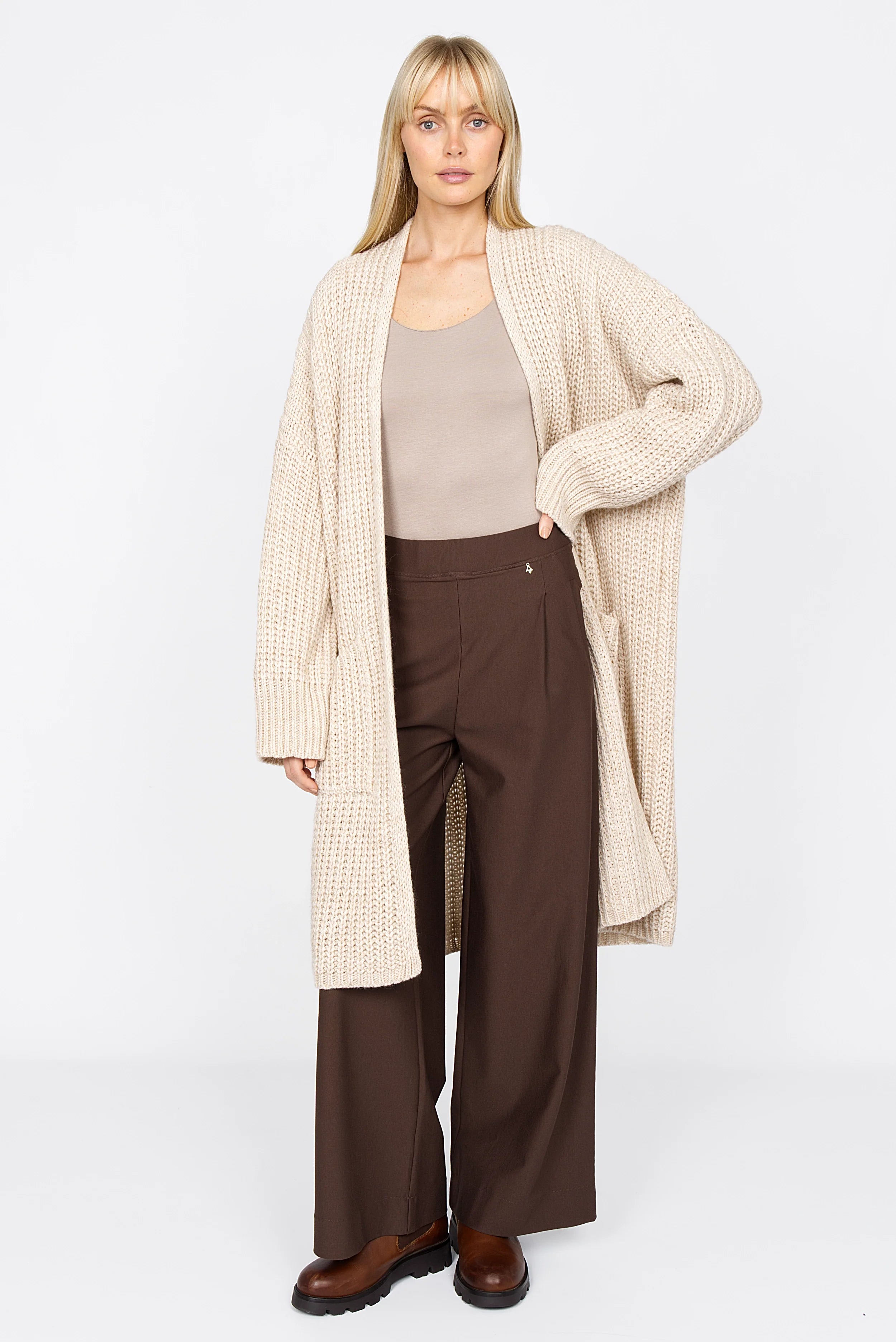 Frau trägt KLARA.K Wide Leg Pants in Braun mit elastischem Bund und seitlichen Eingrifftaschen kombiniert mit beigem Cardigan und Top