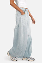 Lightweight Italian denim weite Barrel Jeans with bleached blue wash, subtle destroyed details, raw-cut hem, and relaxed fit