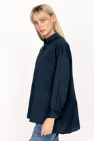 Woman wearing navy LEA.K Loose Fit Bluse with hem collar, chest pockets, and extended back length