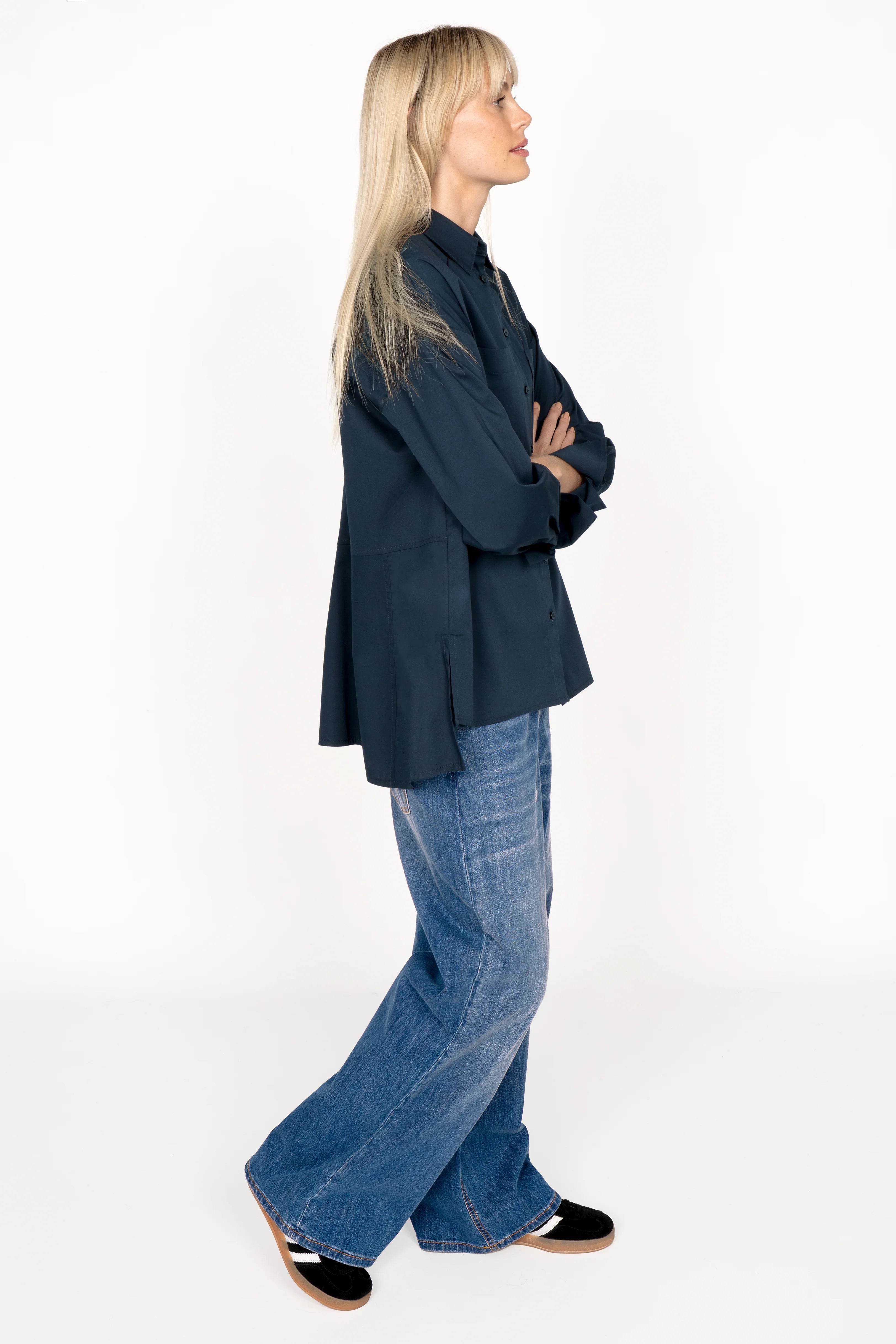 Woman wearing a navy LEA.K Loose Fit Bluse with hem collar, chest pockets, and longer back paired with blue jeans.