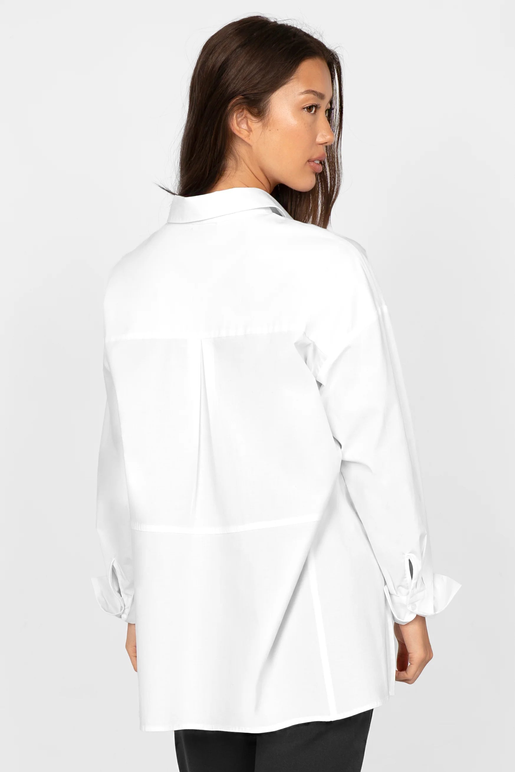 Woman wearing white LEA.K Loose Fit cotton poplin blouse with back pleat and extended hem