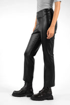 Side view of LIMGARD Flared Eco-Lederhose high-waist cropped black leather pants with flared legs and elastic waistband worn with black boots
