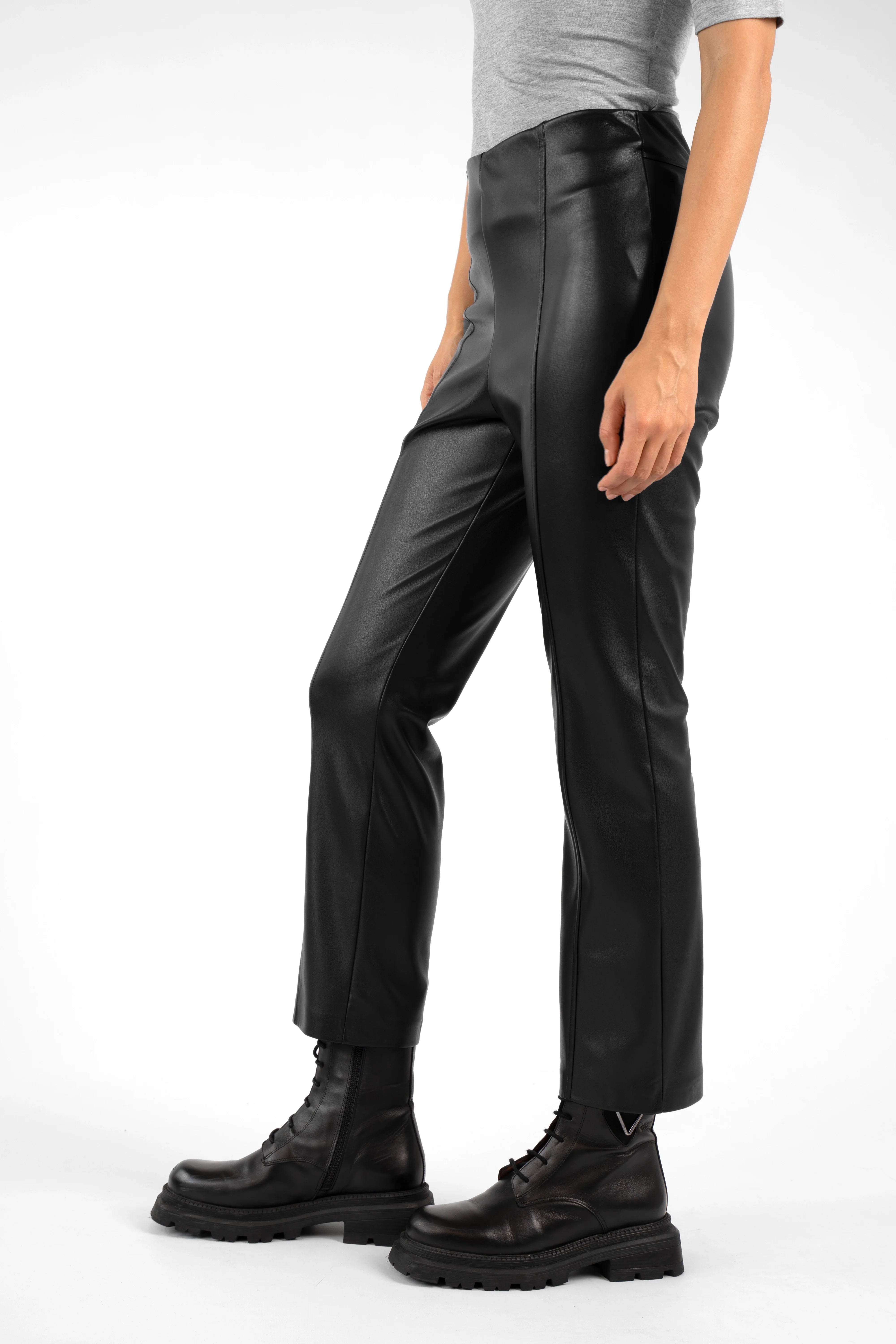 Side view of LIMGARD Flared Eco-Lederhose high-waist cropped black leather pants with flared legs and elastic waistband worn with black boots