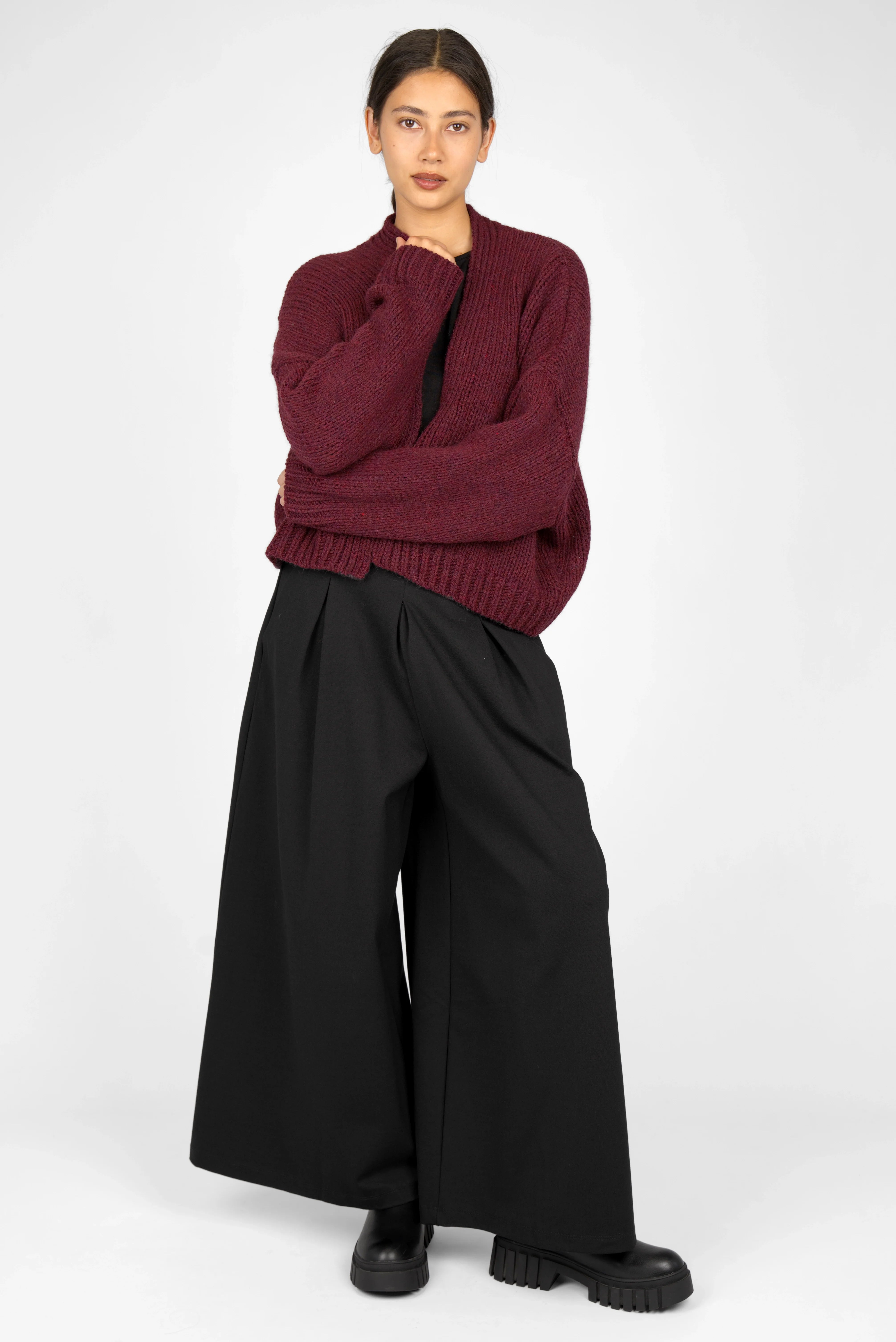 Woman wearing black LINNEE Wide-Leg-Hose with elastic waistband and front pleats paired with a burgundy sweater and black shoes.