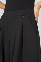 Schwarze LINNEE Wide-Leg-Hose aus weicher Interlock-Qualität mit elastischem Bund, Bundfalten und seitlichen Taschen.