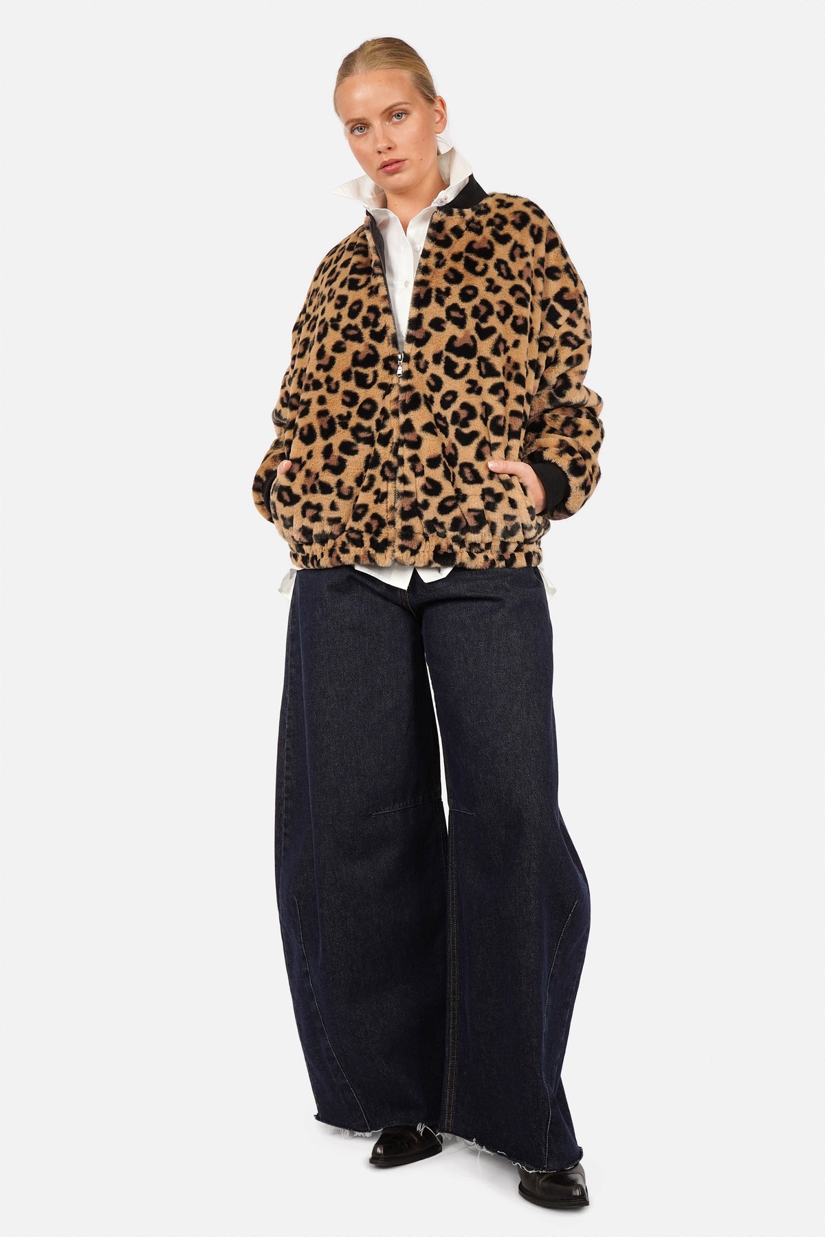 LIORA Kunstpelz-Bomberjacke mit Leopardenmuster, kombiniert mit weißer Bluse und weiter dunkler Jeans
