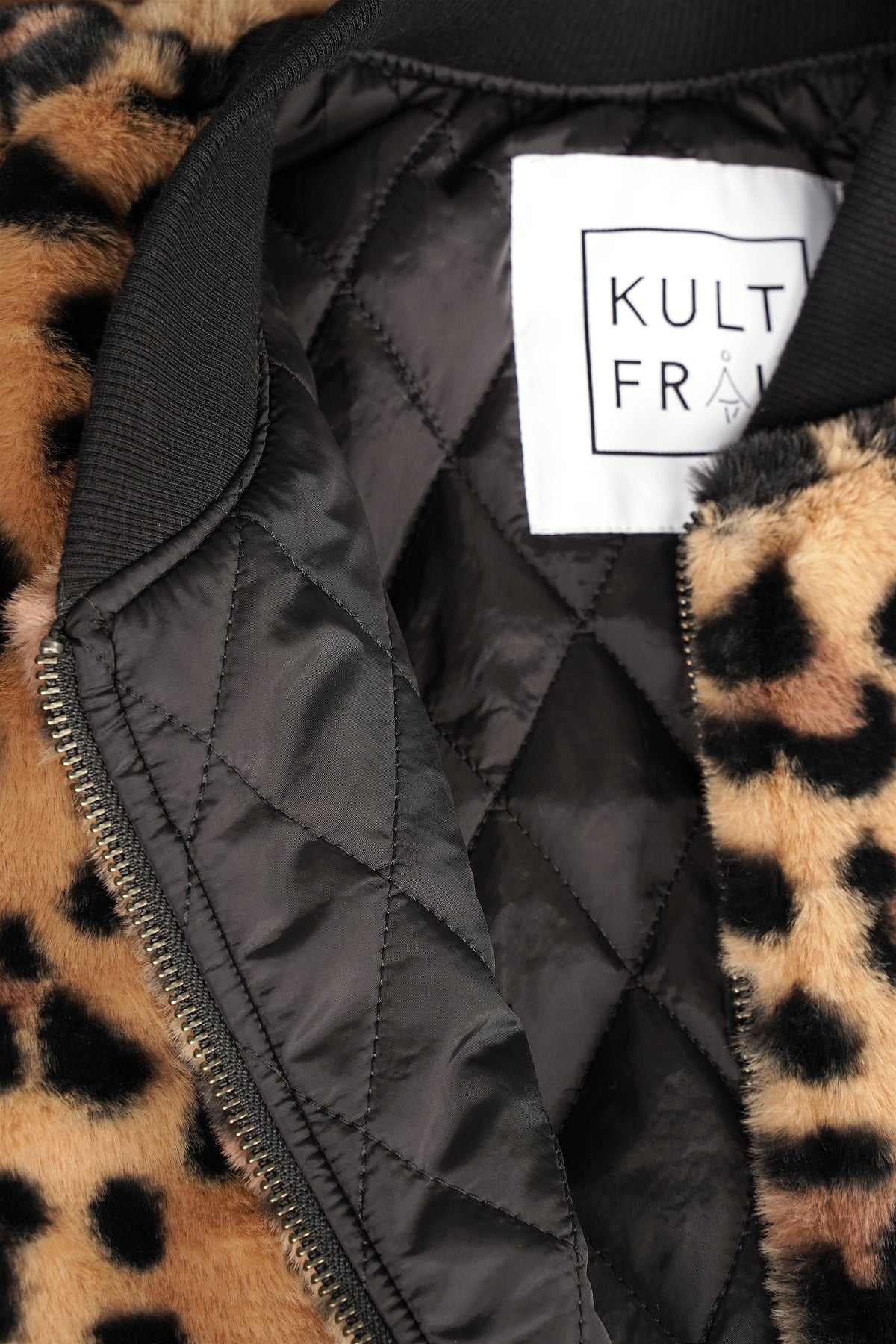 Detail der LIORA Bomberjacke mit schwarzem gestepptem Innenfutter, Rippkragen und KULTFRAU-Etikett