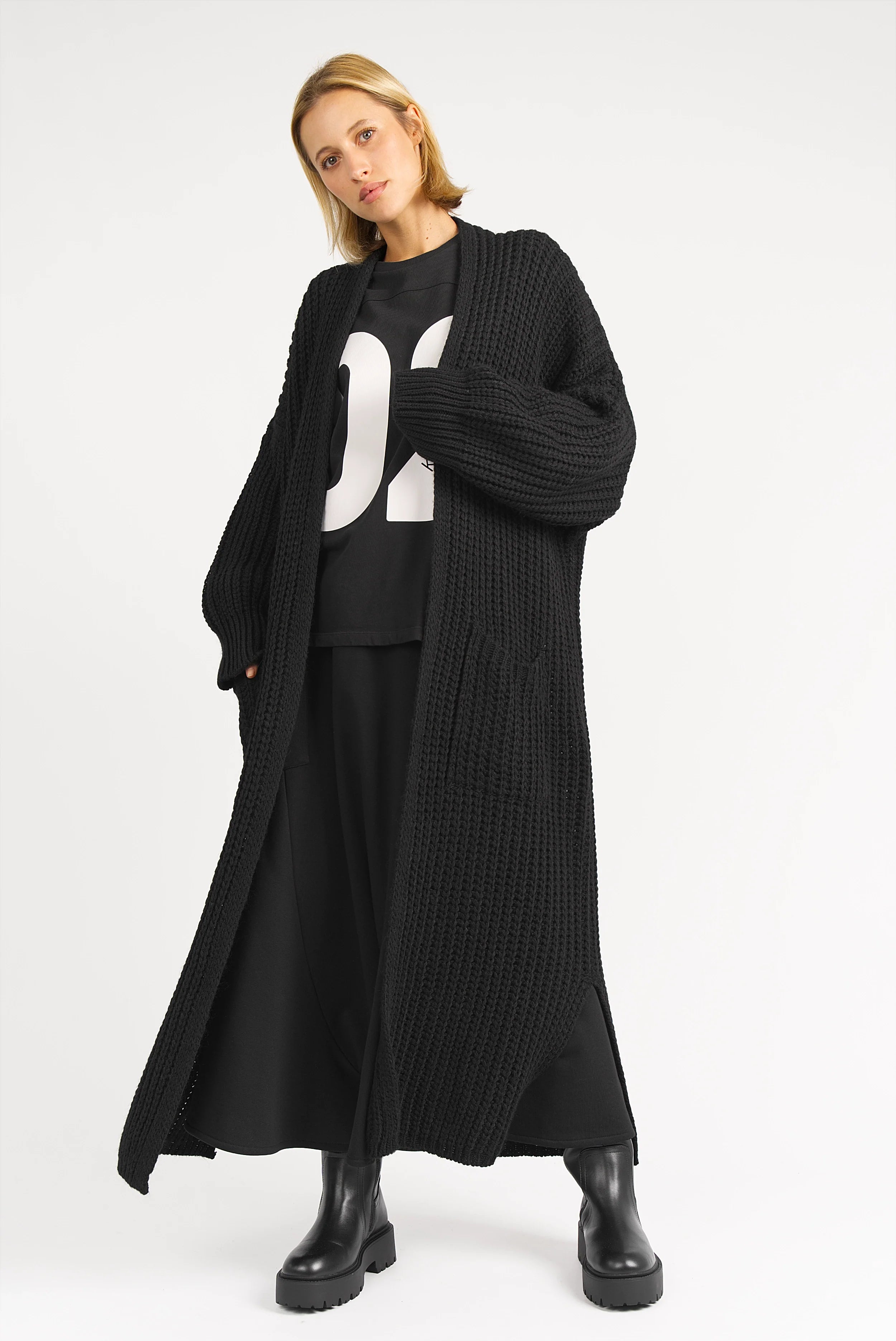 Damen trägt langen schwarzen LOLA Strickcardigan oversized mit aufgesetzten Taschen und lockerem Schnitt