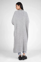 Woman wearing a long, gray oversized LOLA Strickcardigan with a relaxed fit and open front, viewed from the back.