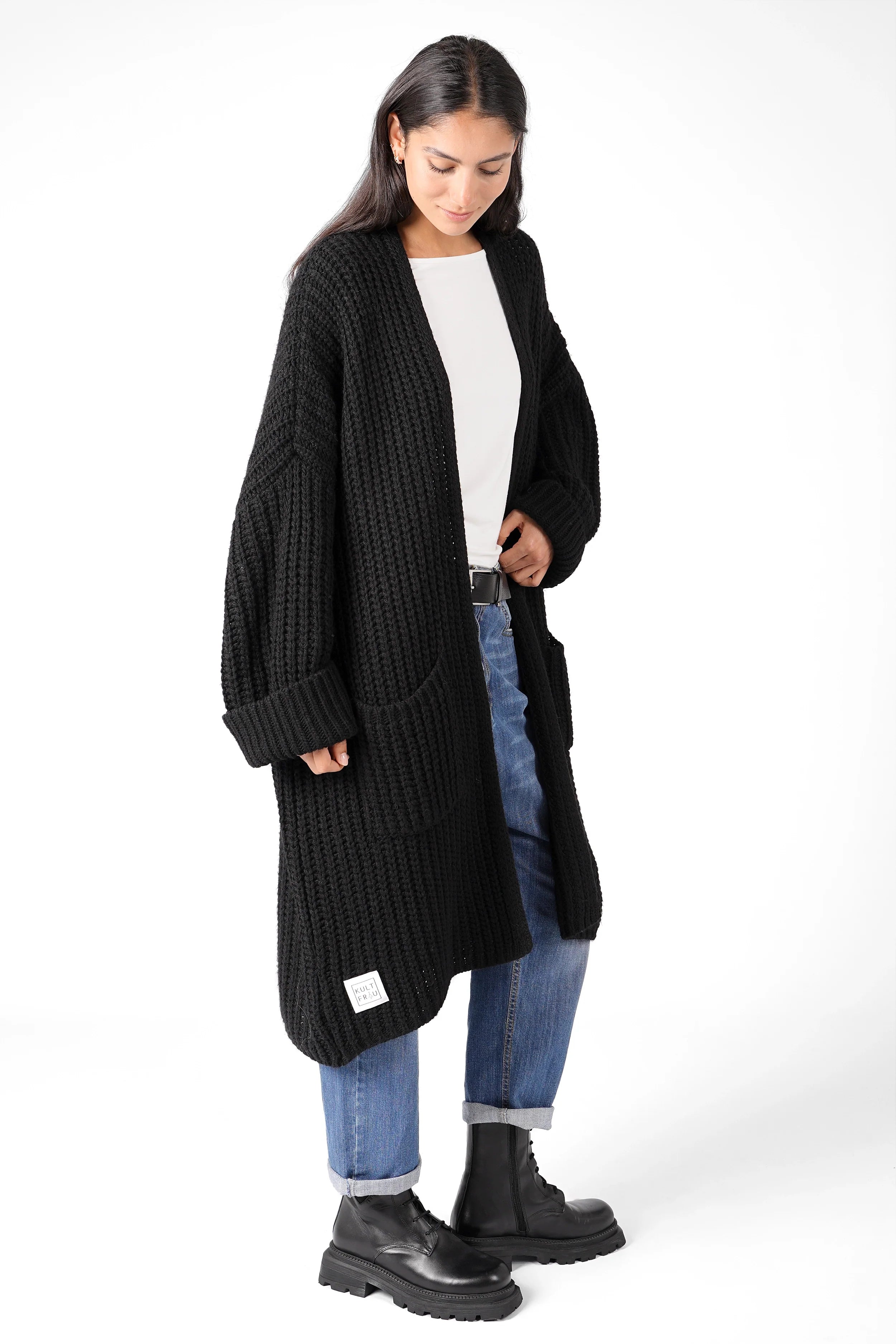 Woman wearing black LOLLYTA Strickcardigan oversized knit with rolled sleeves and front pockets over white top and blue jeans