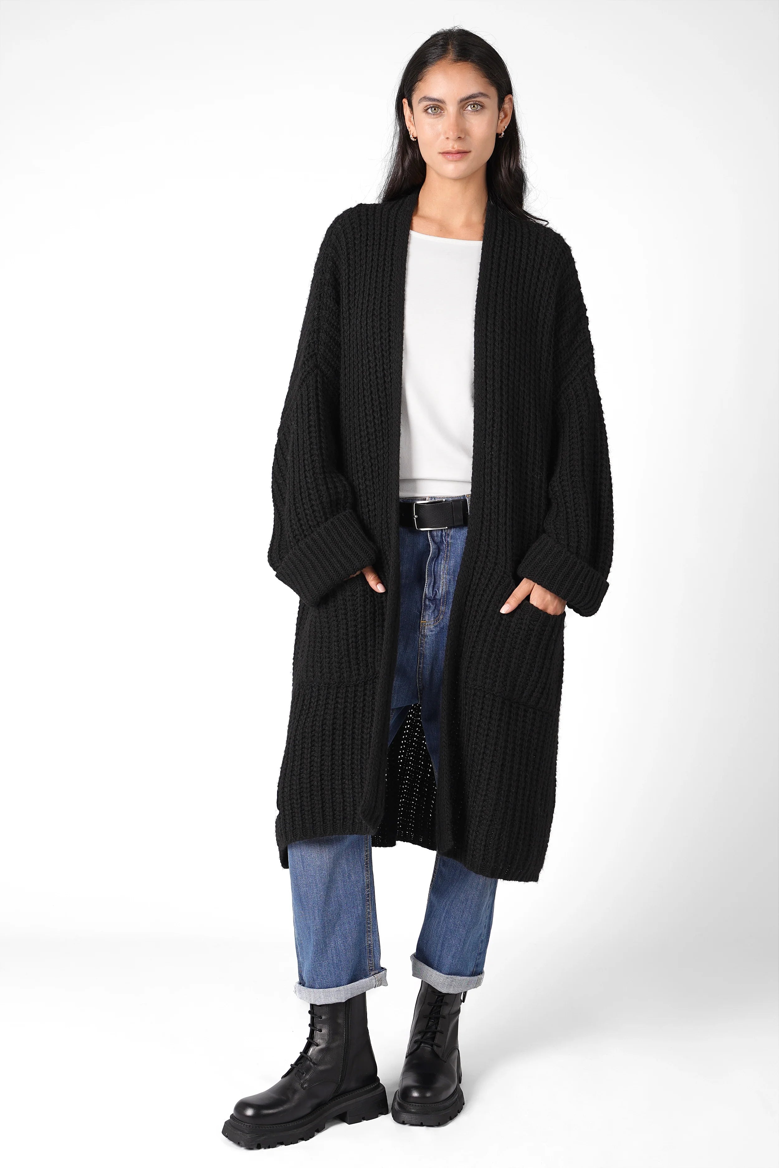 Woman wearing oversized black LOLLYTA Strickcardigan with rolled sleeves, front pockets, and relaxed fit over white top and blue jeans.
