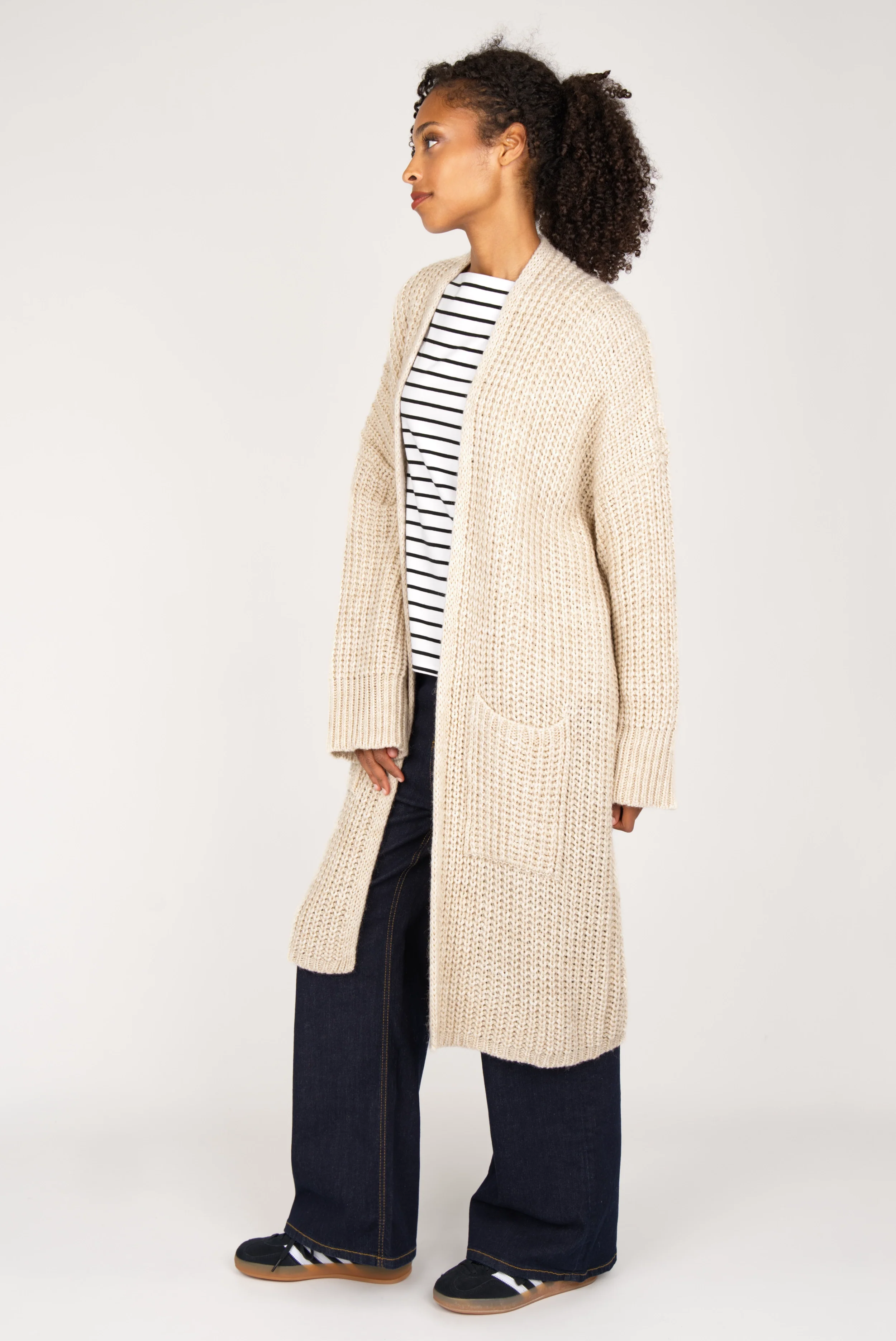 Woman wearing oversized beige LOLYTA Strickcardigan with pockets over striped shirt and wide-leg jeans