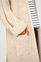 LOLYTA Strickcardigan beige oversized knit cardigan with cuffed sleeves and front pocket worn open over striped top