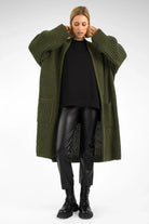 Woman wearing oversized olive green LOLLYTA Strickcardigan with relaxed fit, open front, and patch pockets over black outfit