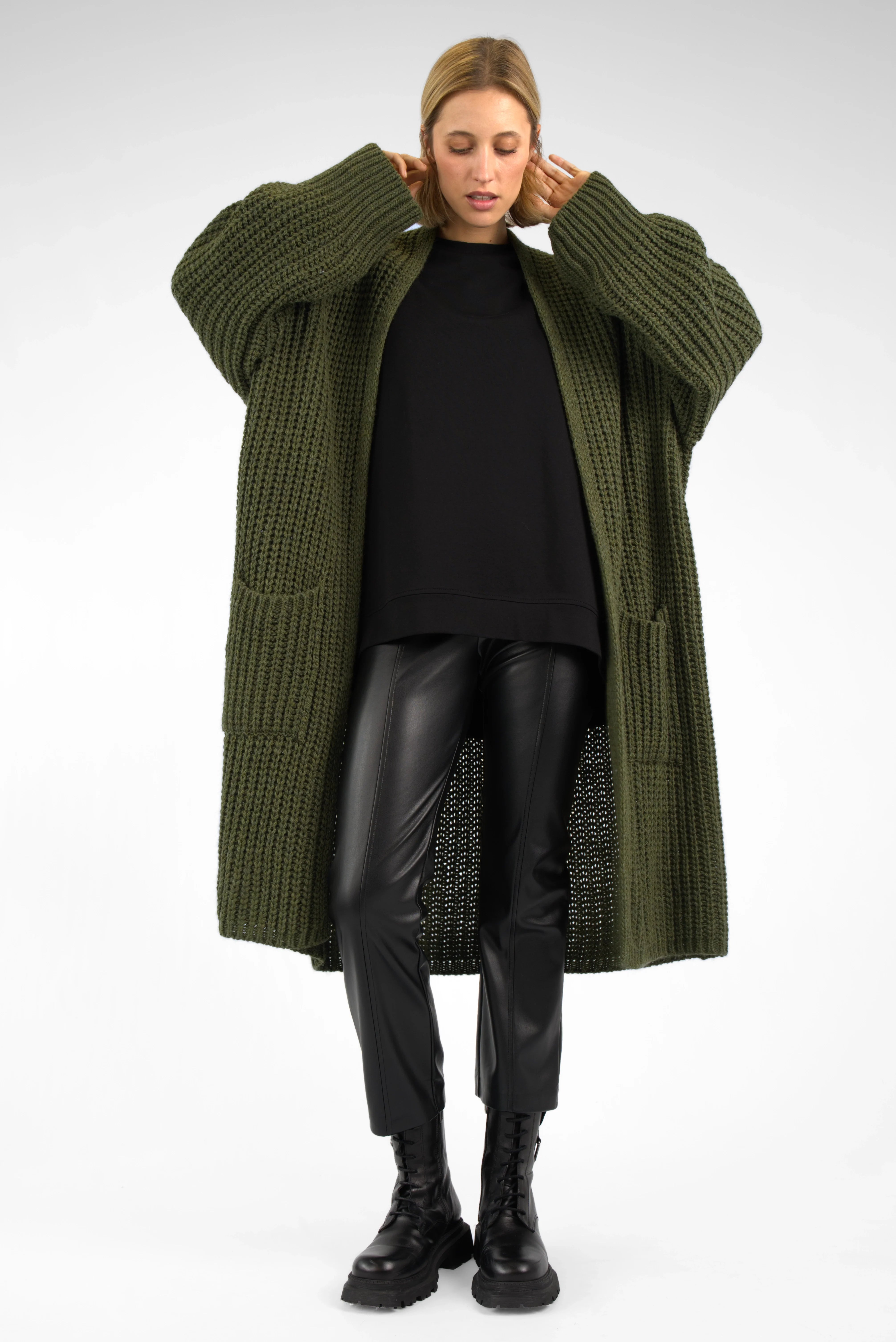 Woman wearing oversized olive green LOLLYTA Strickcardigan with relaxed fit, open front, and patch pockets over black outfit