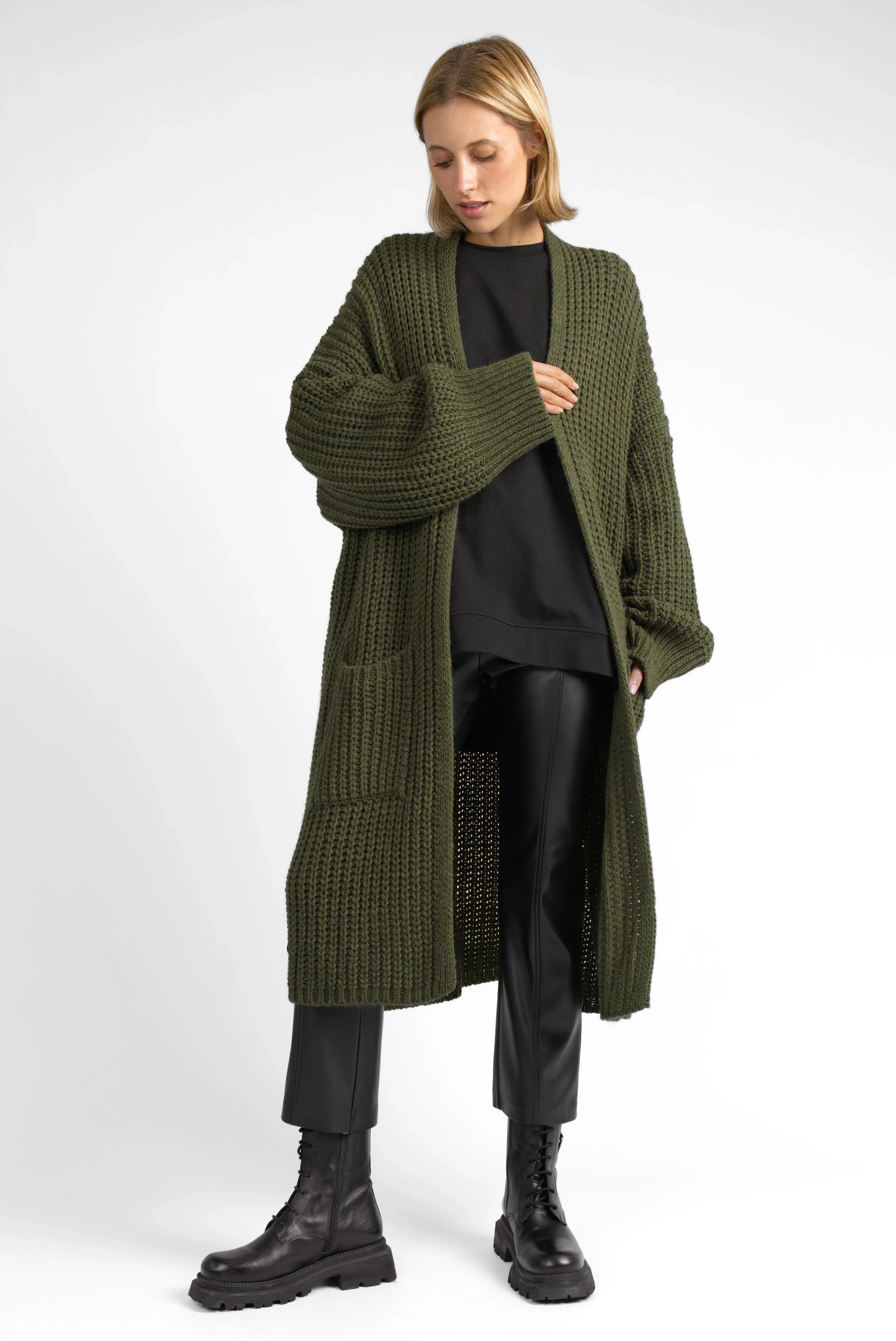 Damenmodel trägt oversize LOLLYTA Strickcardigan offen mit aufgesetzten Taschen und grobem Strick in Olivgrün