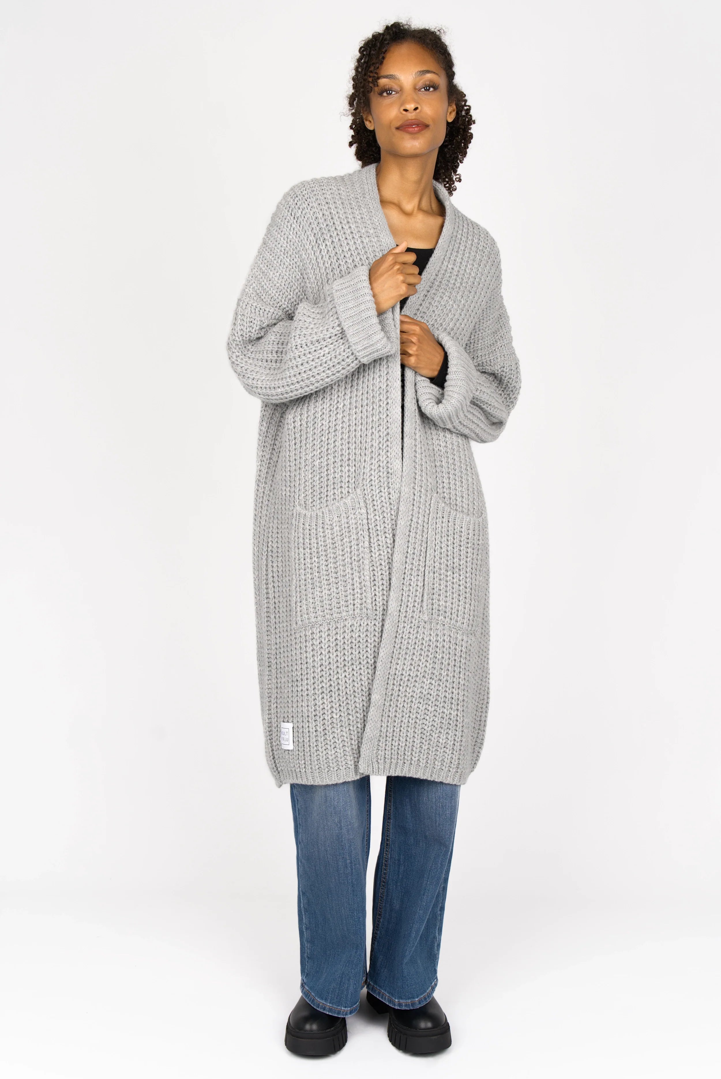 Woman wearing oversized grey LOLLYTA Strickcardigan with relaxed fit and front pockets over casual jeans