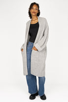Woman wearing oversized grey LOLLYTA Strickcardigan with rolled sleeves, open front, and front pockets over black top and blue jeans