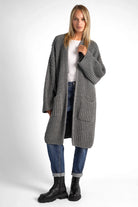 Woman wearing grey oversized LOLLYTA Strickcardigan with pockets, open front, and relaxed fit over jeans and boots