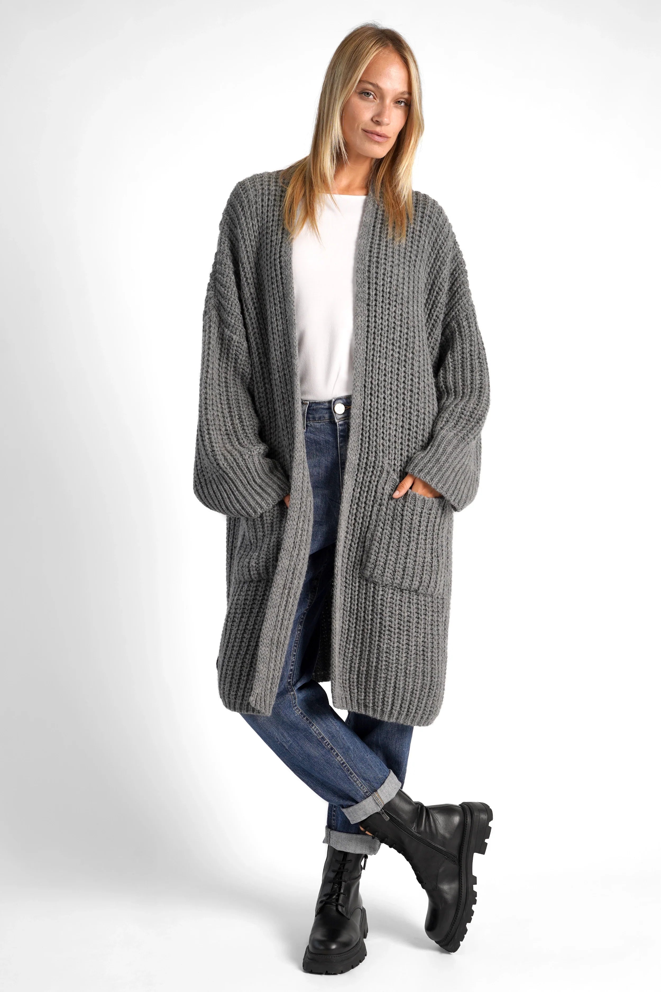 Woman wearing a grey oversized LOLLYTA Strickcardigan with dropped shoulders, patch pockets, and relaxed fit over white top and jeans.