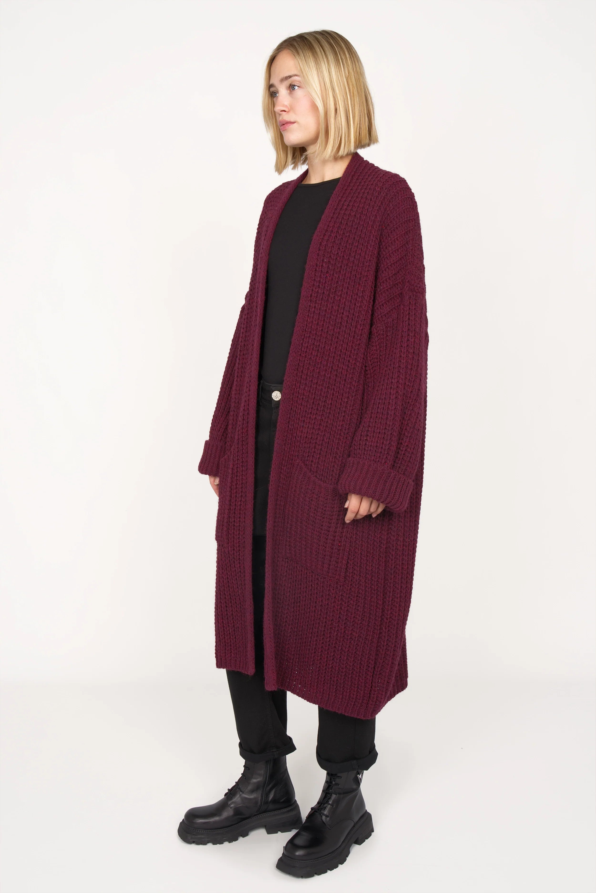 Woman wearing oversized maroon LOLLYTA Strickcardigan with rolled sleeves and patch pockets over black outfit