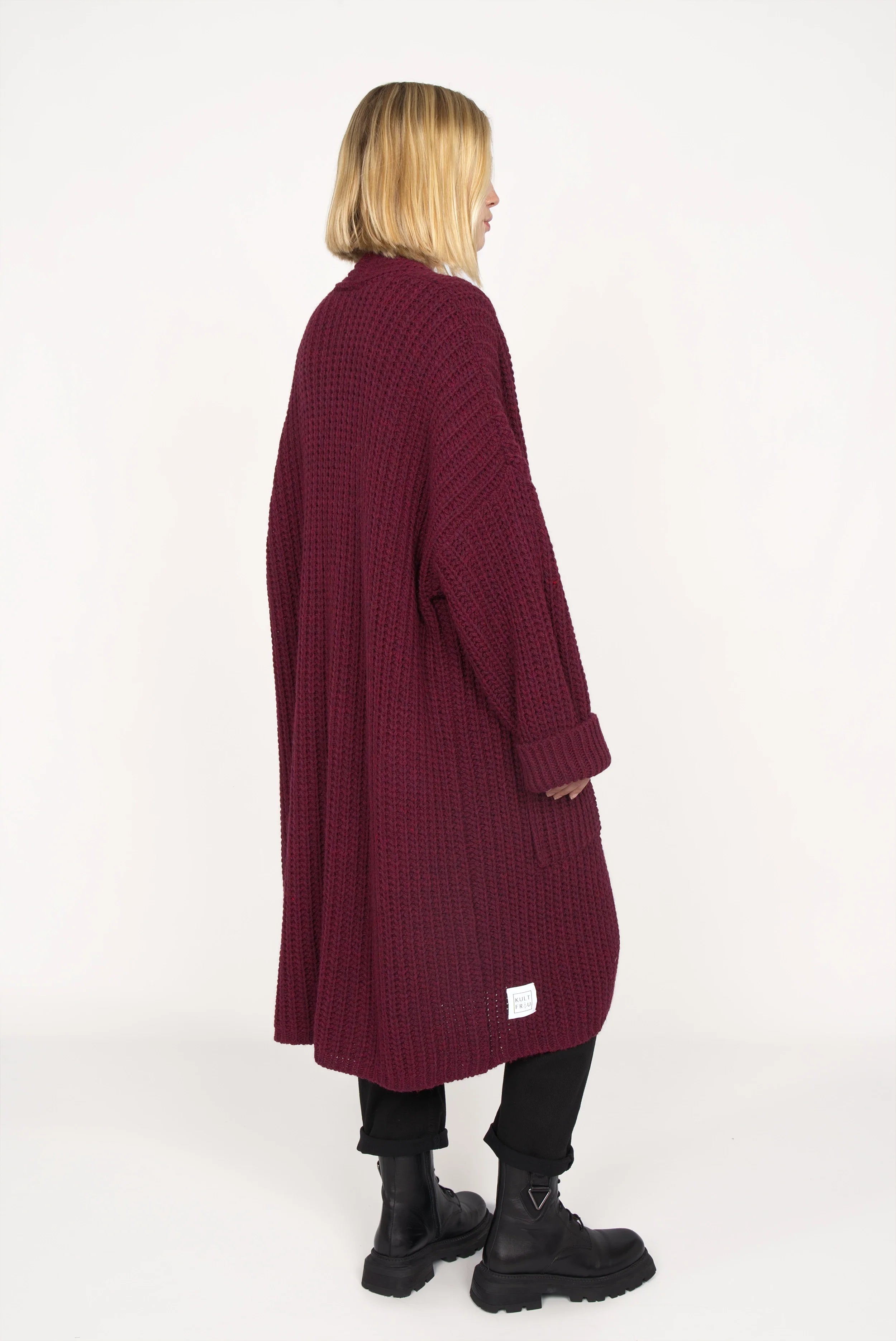 Woman wearing oversized LOLLYTA Strickcardigan in deep burgundy with rolled sleeves and black boots.