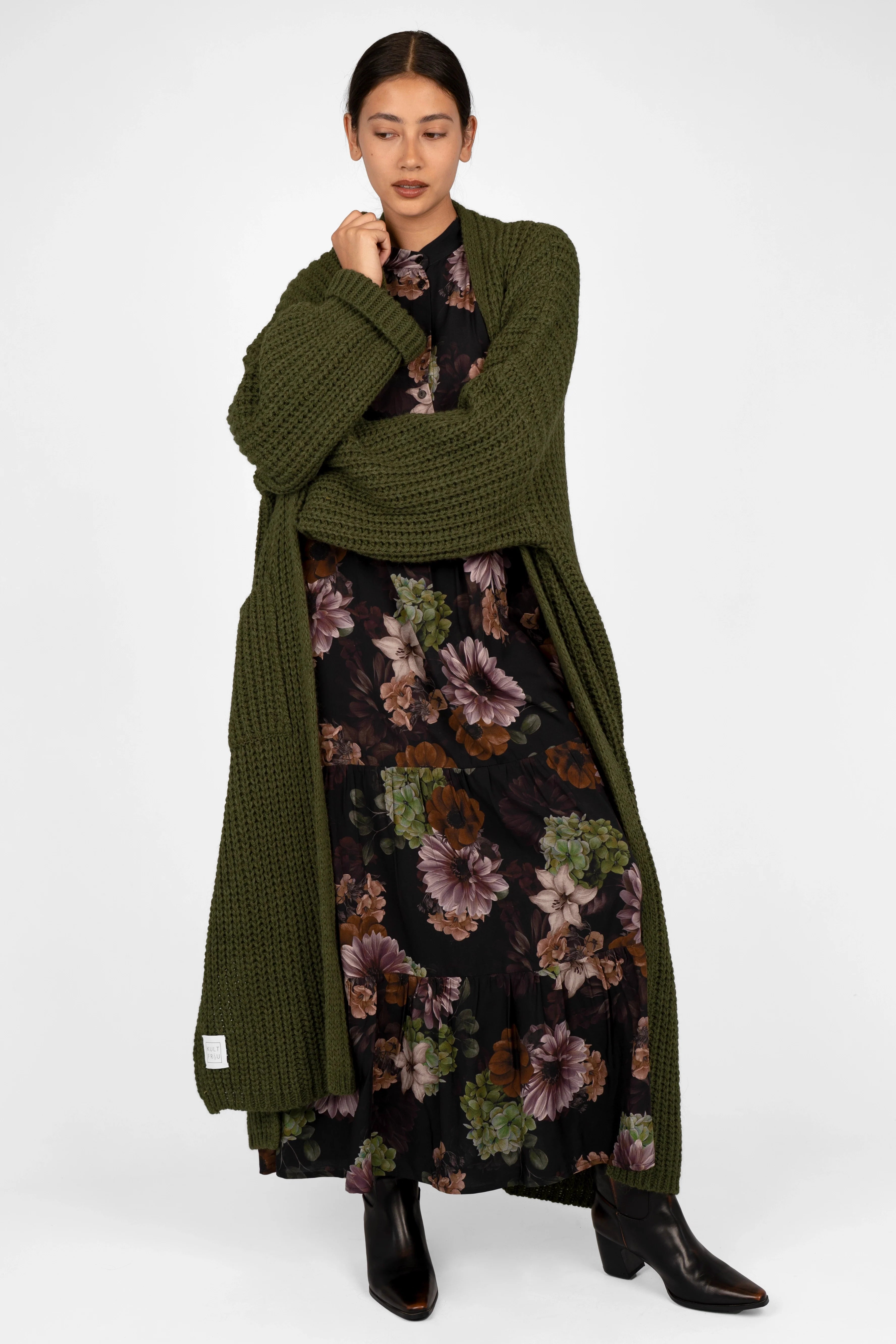 Woman wearing LUSIIA Maxikleid floral print maxi dress with standing collar and side pockets paired with green knitted cardigan and black boots