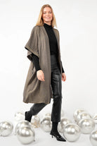 Frau trägt fließenden Kimono aus Viskosemischung mit Metallic-Finish, Schalkragen und weiten Ärmeln, kombiniert mit schwarzer Kleidung und Stiefeletten.