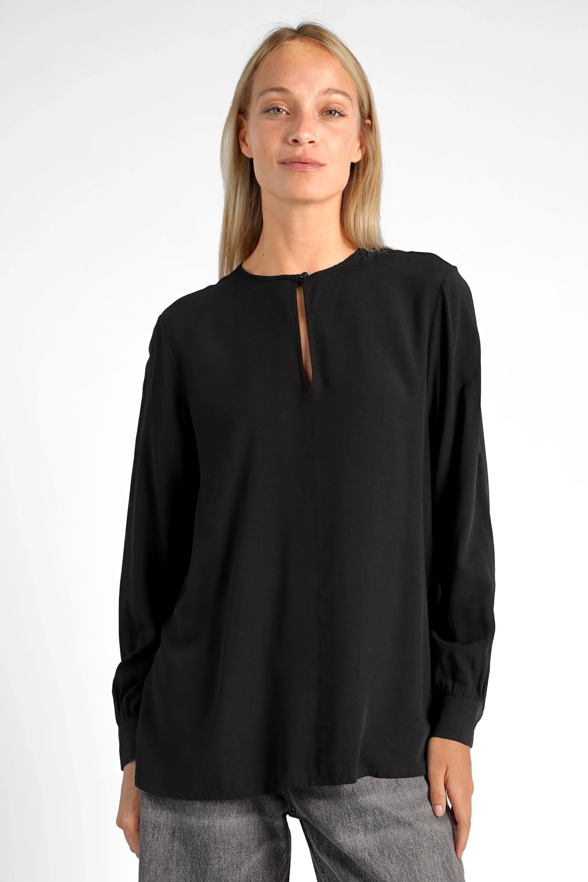Black loose fit blouse with V-neck button detail and long sleeves on model