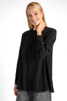 Woman wearing black LYLIA.K loose fit blouse with V-neck and long sleeves