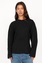 Black MALVEA Sweater with structured seams and relaxed fit worn by woman