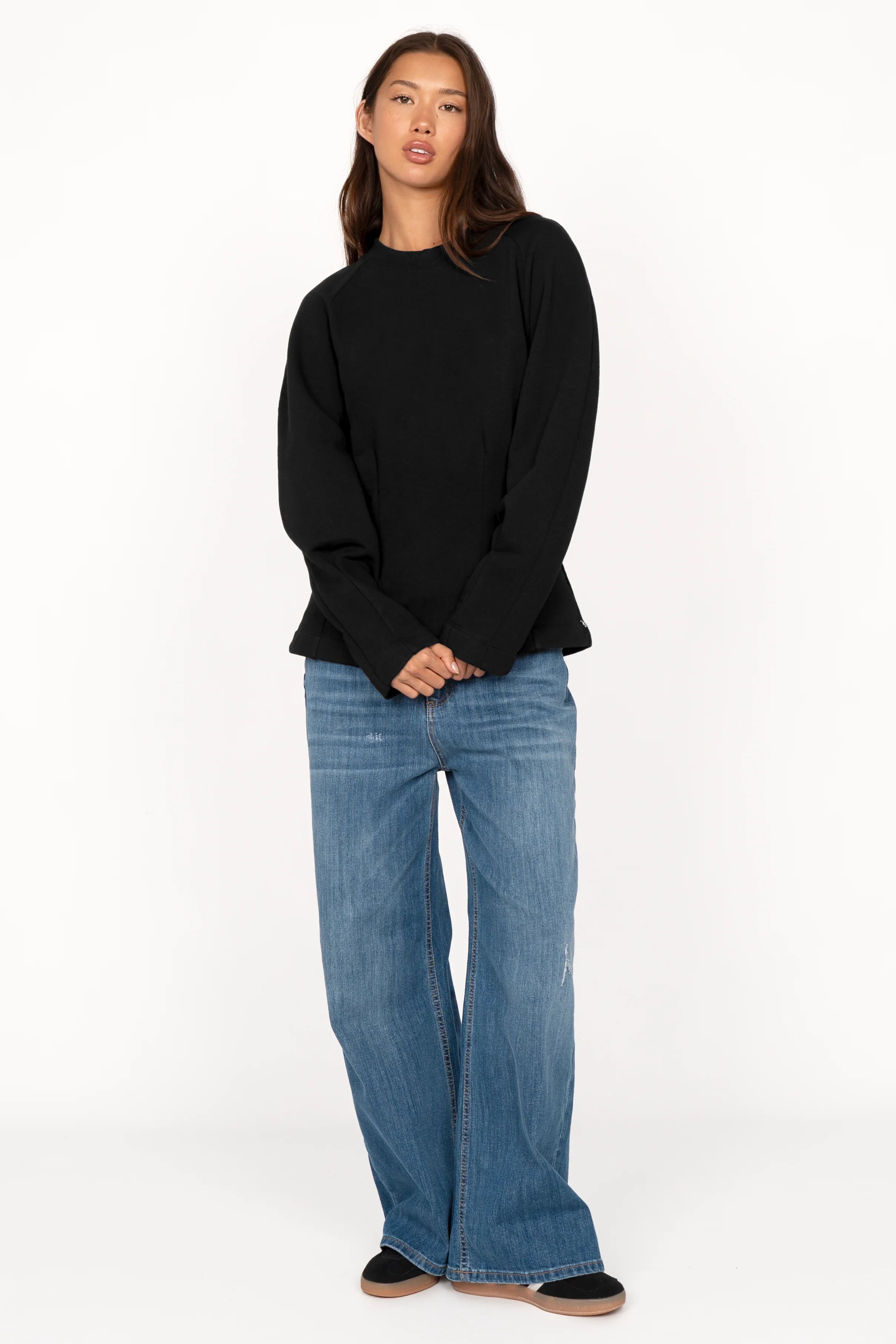 Woman wearing black MALVEA Sweater with relaxed fit and blue jeans