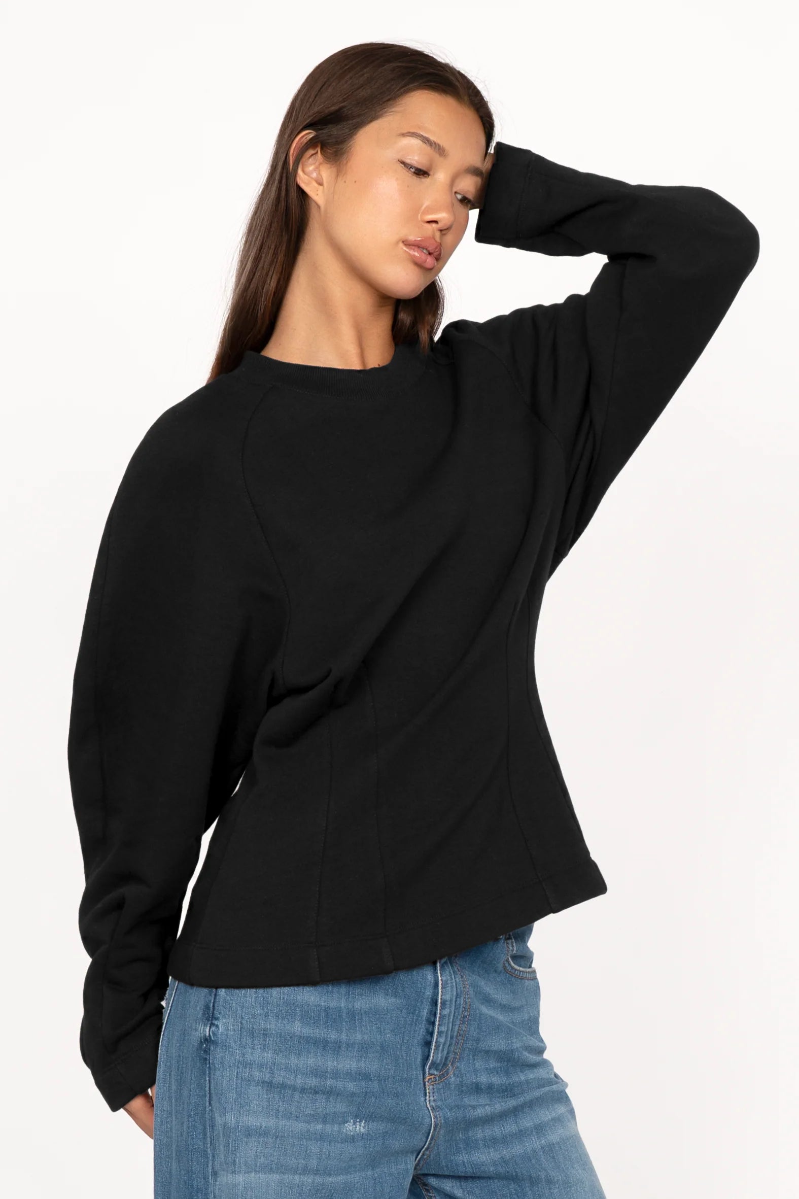 Black MALVEA Sweater with relaxed fit, round neckline, and subtle seam details on a model wearing blue jeans.